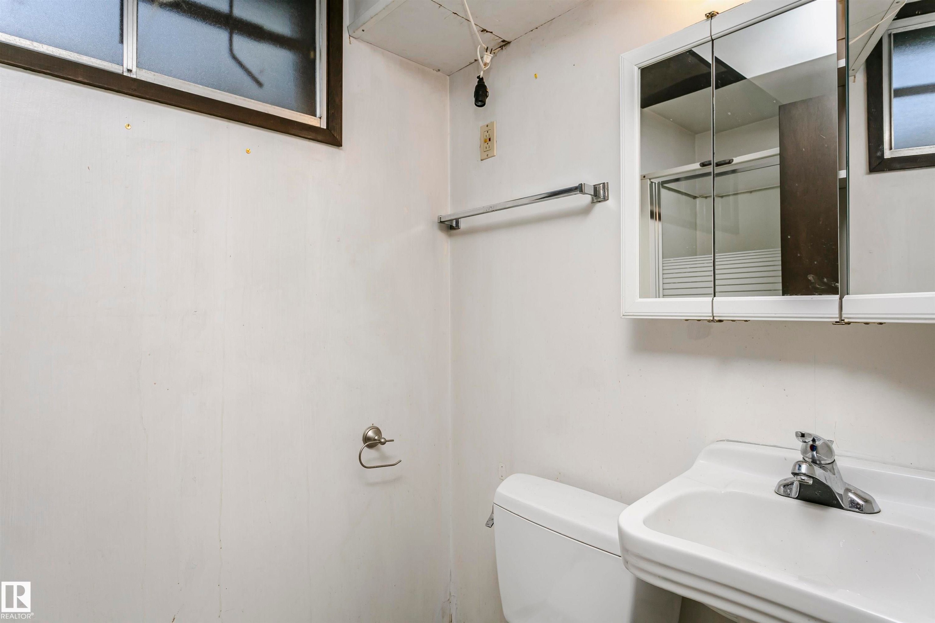 Wall-mounted sink with chrome faucet, white toilet, and medicine cabinet with mirrored doors - 11440 44A Avenue Nw, Edmonton, AB