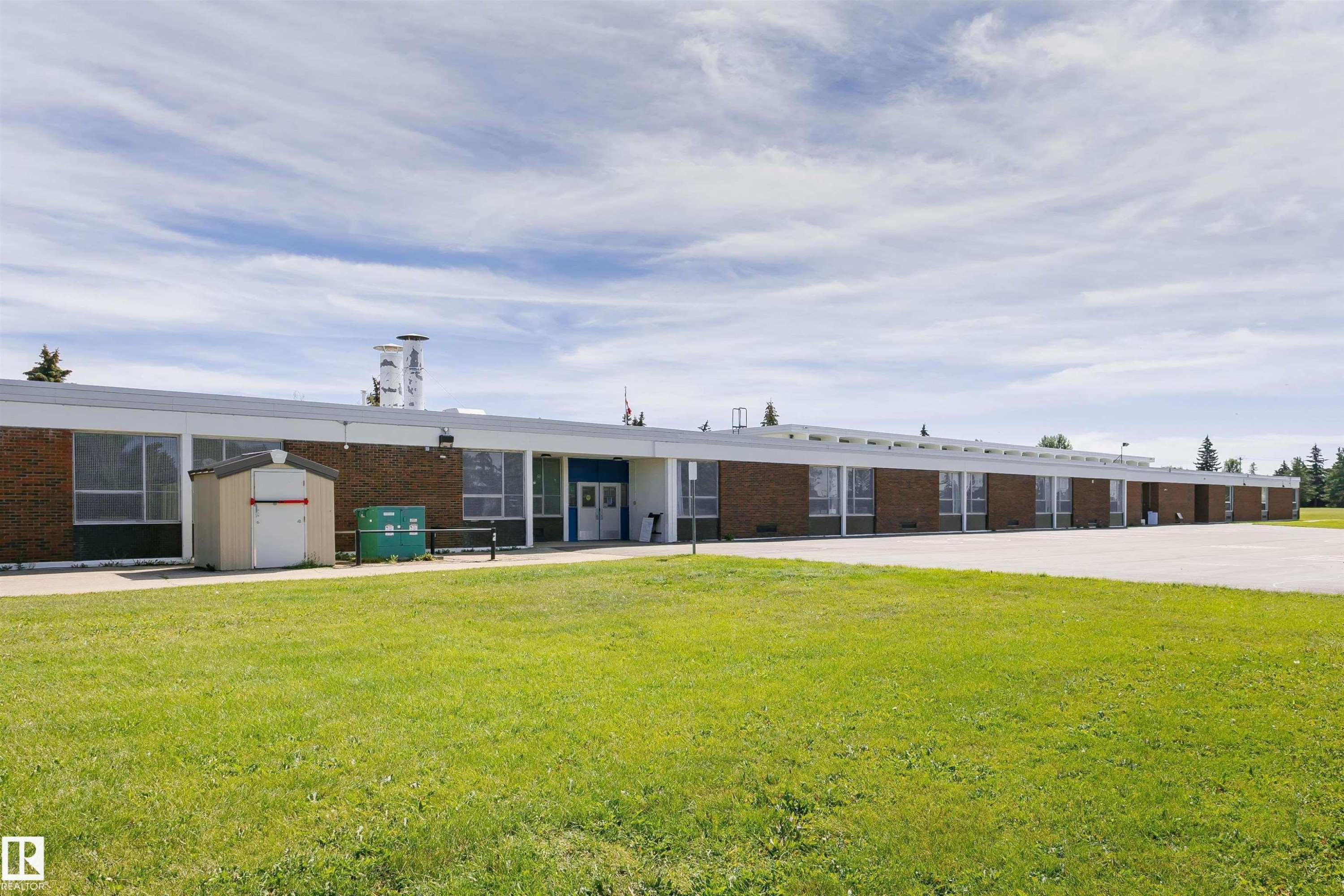 Brick exterior with a flat roofline, multiple windows, and a paved lot - 11440 44A Avenue Nw, Edmonton, AB