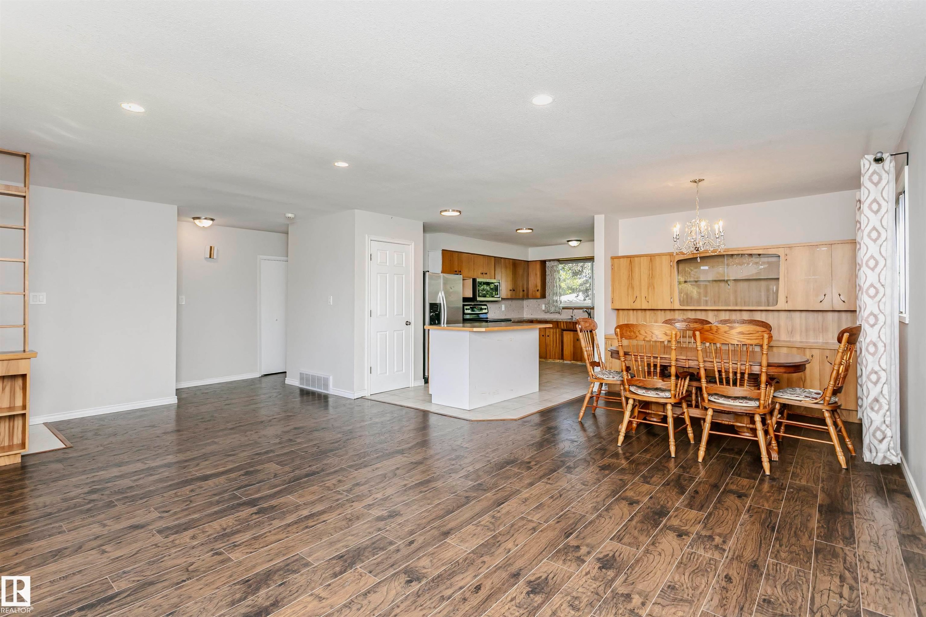 Open-concept layout featuring wood-finish flooring, recessed lighting, and a kitchen island with a light-toned countertop - 11440 44A Avenue Nw, Edmonton, AB