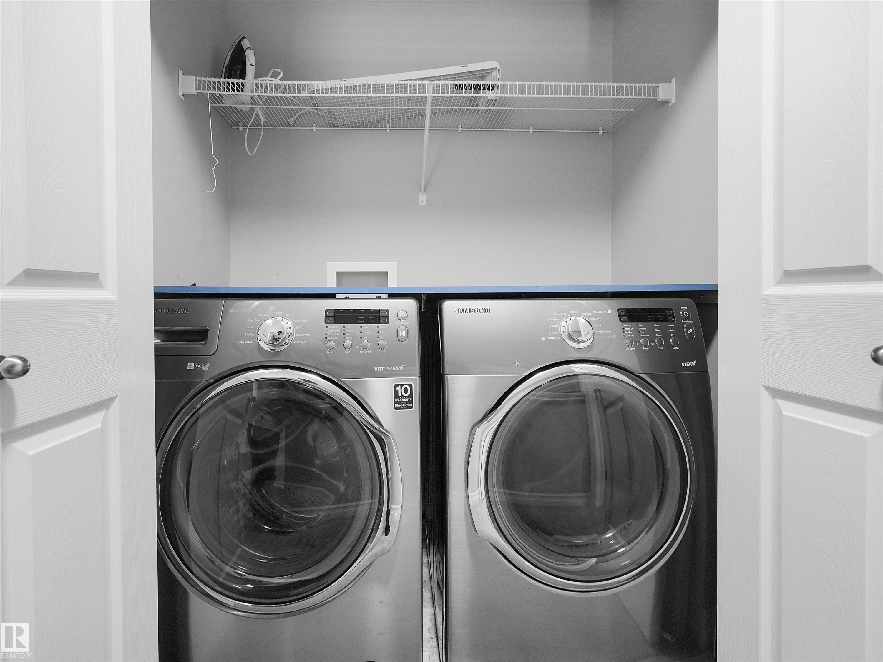 Laundry closet with bi-fold doors, wire shelving, and overhead cabinet - 5190 1B Avenue Sw, Edmonton, AB