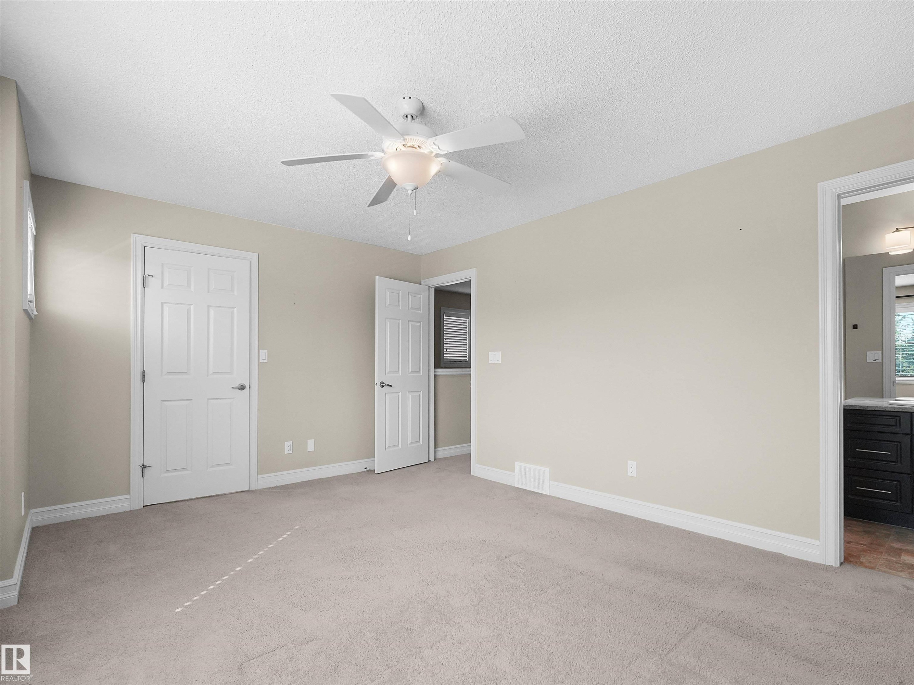 Neutral wall paint, plush carpet flooring, ceiling fan with integrated lighting, white trim, and white paneled doors - 5190 1B Avenue Sw, Edmonton, AB