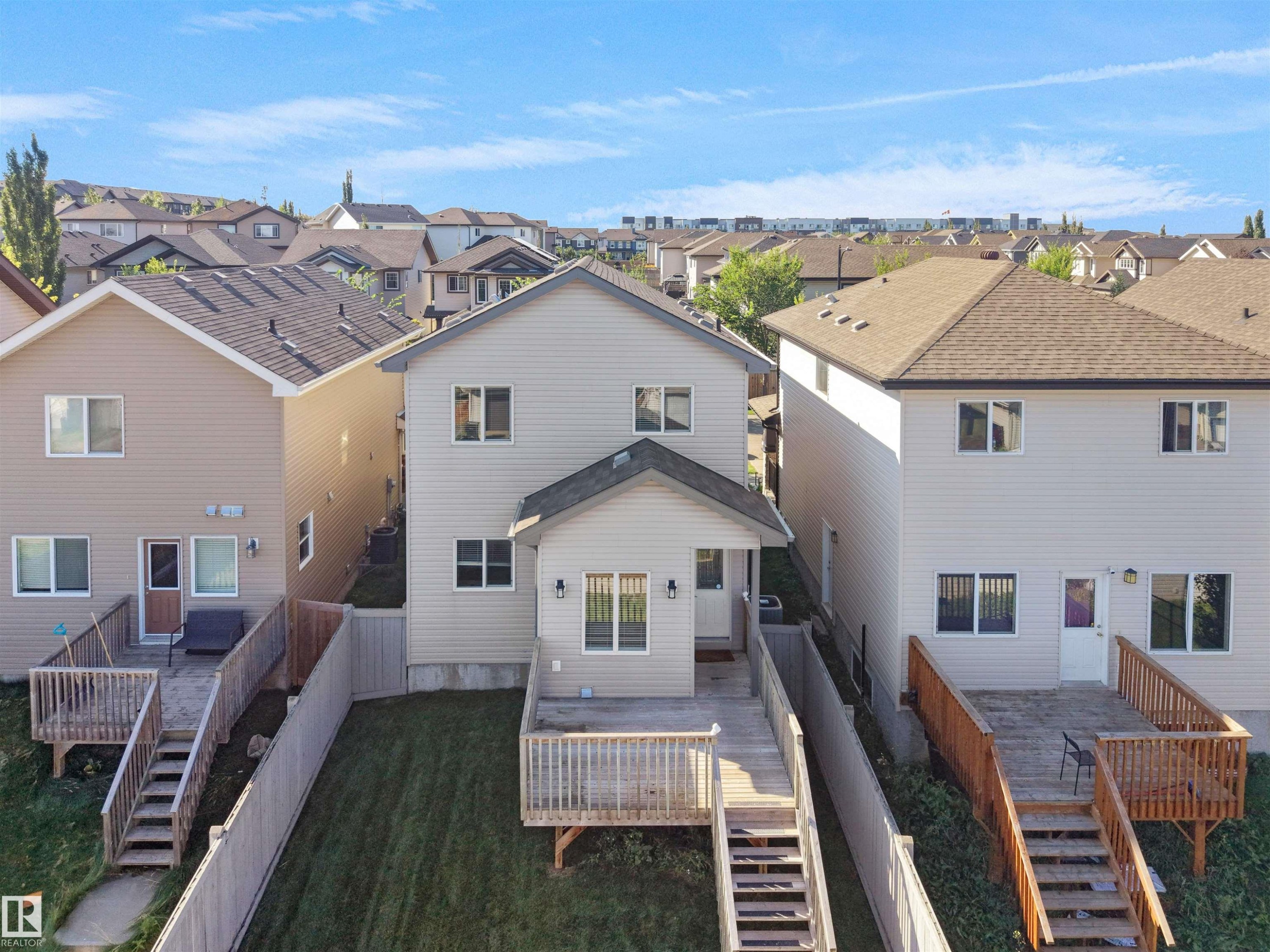 Rear exterior with two-story siding, covered patio, and wood deck with railings - 5190 1B Avenue Sw, Edmonton, AB