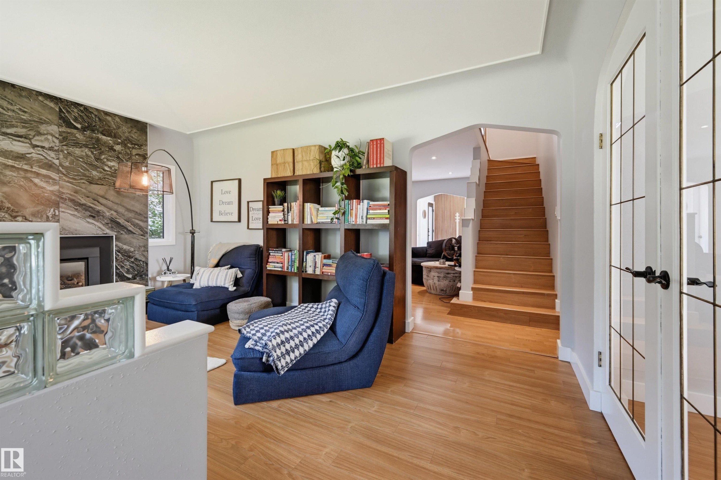 Hardwood flooring, natural stone fireplace surround, built-in shelving, glass block partition, and wood staircase - 10726 128 Street Nw, Edmonton, AB