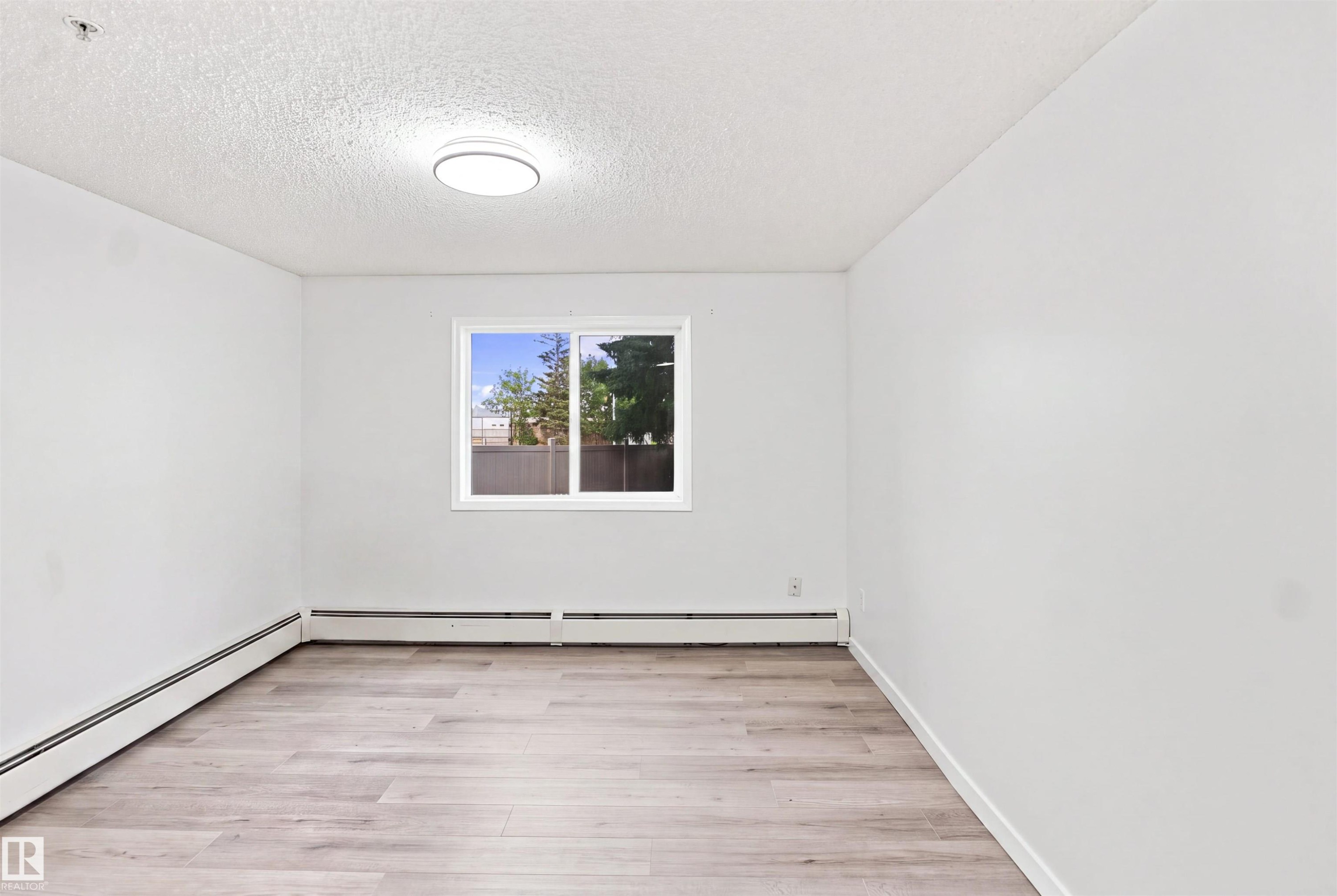 Wood-finish flooring, white walls, and a window with white trim - #124 10511 42 Av Nw, Edmonton, AB