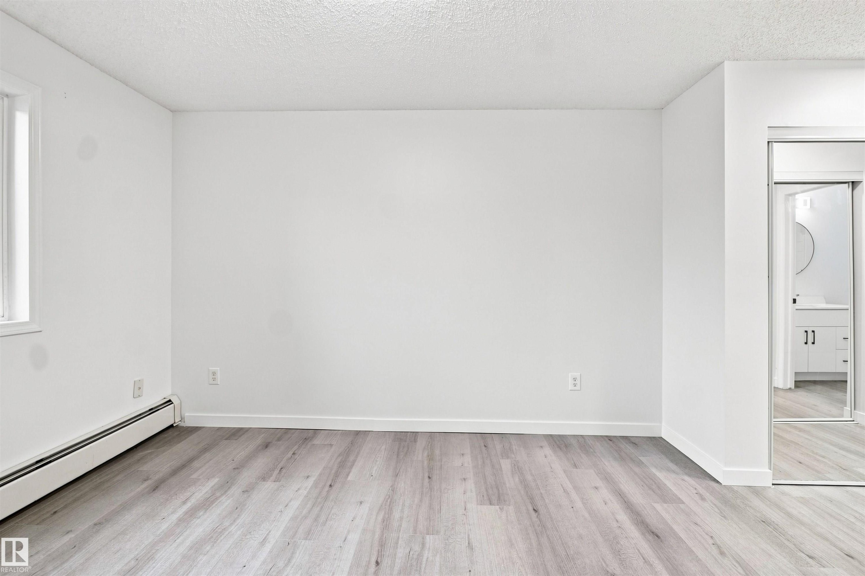 Wood-finish flooring, white painted walls, and a window with white trim - #124 10511 42 Av Nw, Edmonton, AB
