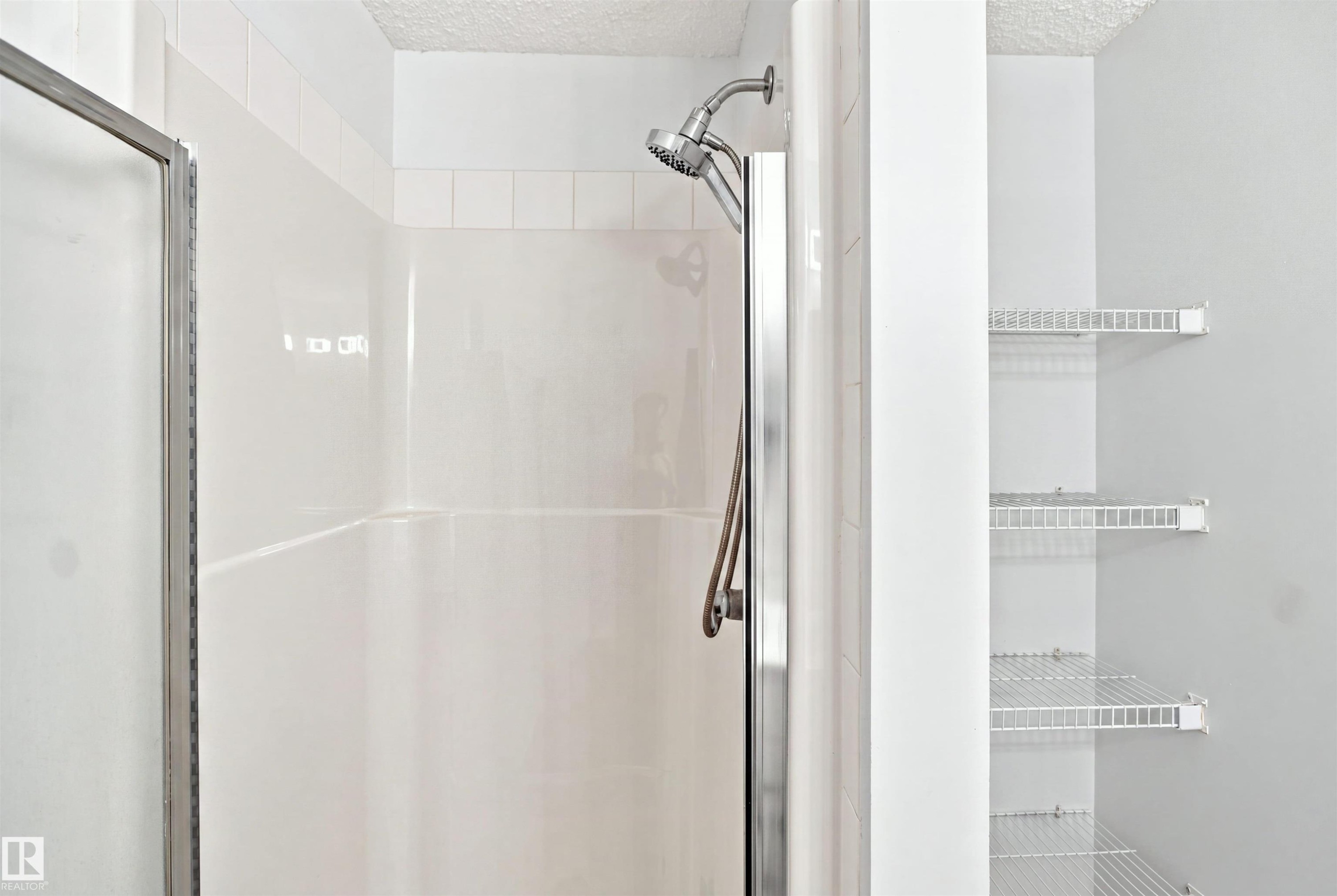 Shower with white tile surround, glass enclosure, and mounted shower head - #124 10511 42 Av Nw, Edmonton, AB