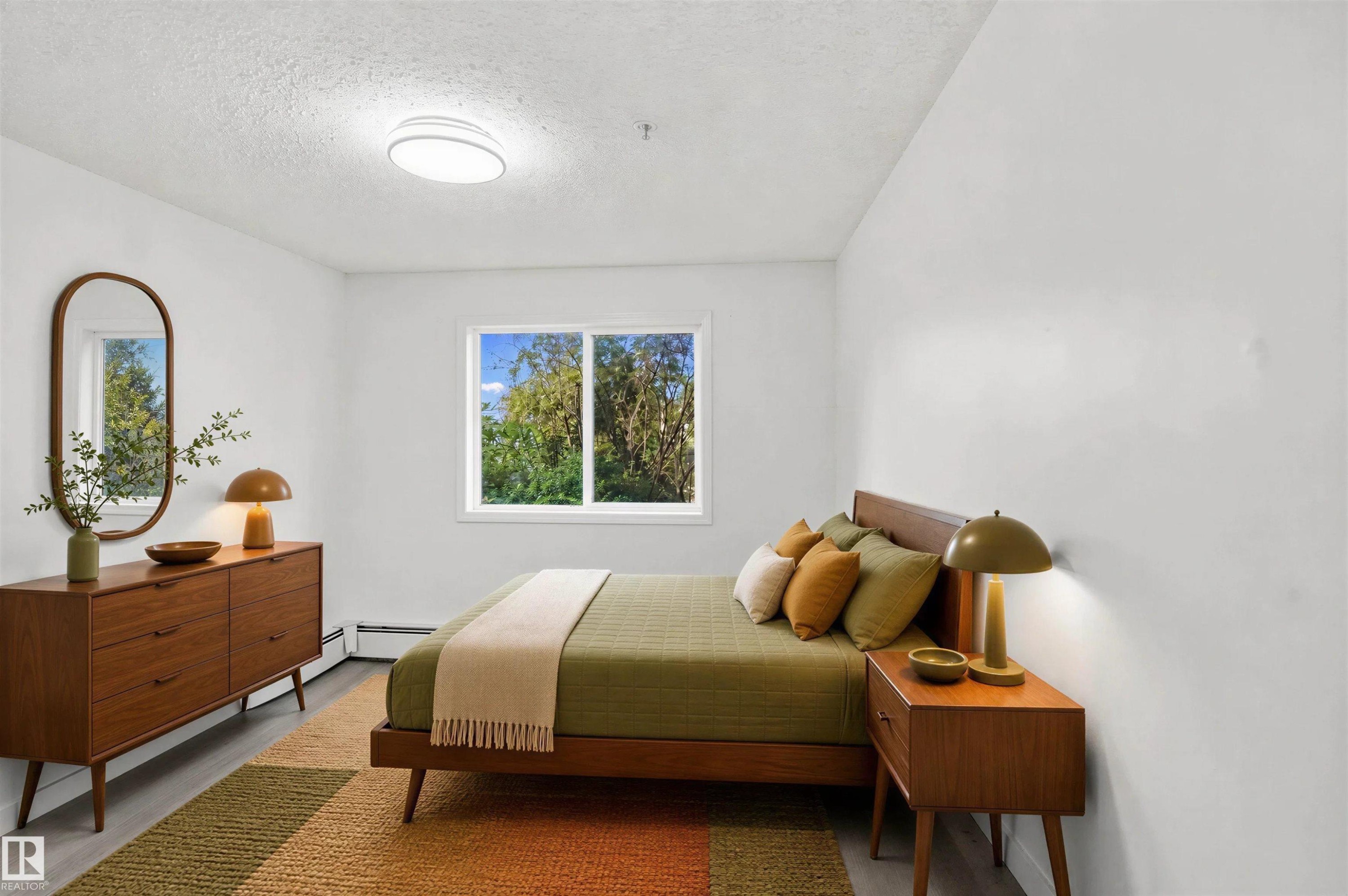 Bright bedroom with a window, overhead flush-mount lighting, and wood-finish flooring - #124 10511 42 Av Nw, Edmonton, AB