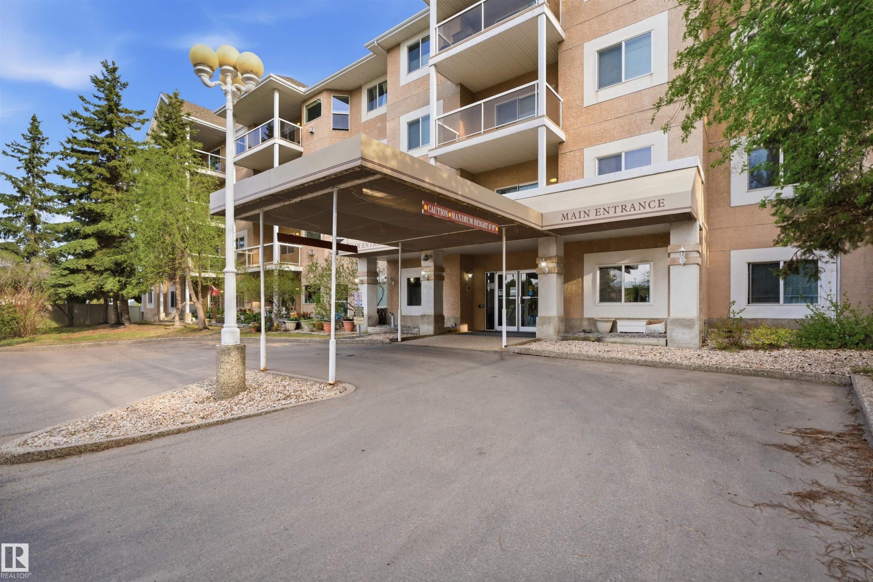 Multi-story building exterior with covered main entrance, glass double doors, and multiple balconies - #124 10511 42 Av Nw, Edmonton, AB