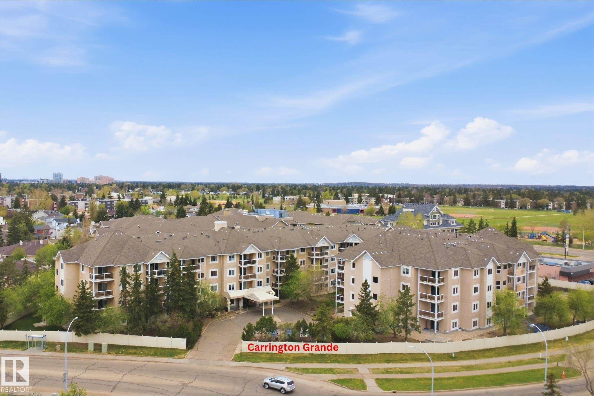 Multi-story residential building featuring multiple balconies, a covered entrance, and surrounding mature trees - #124 10511 42 Av Nw, Edmonton, AB