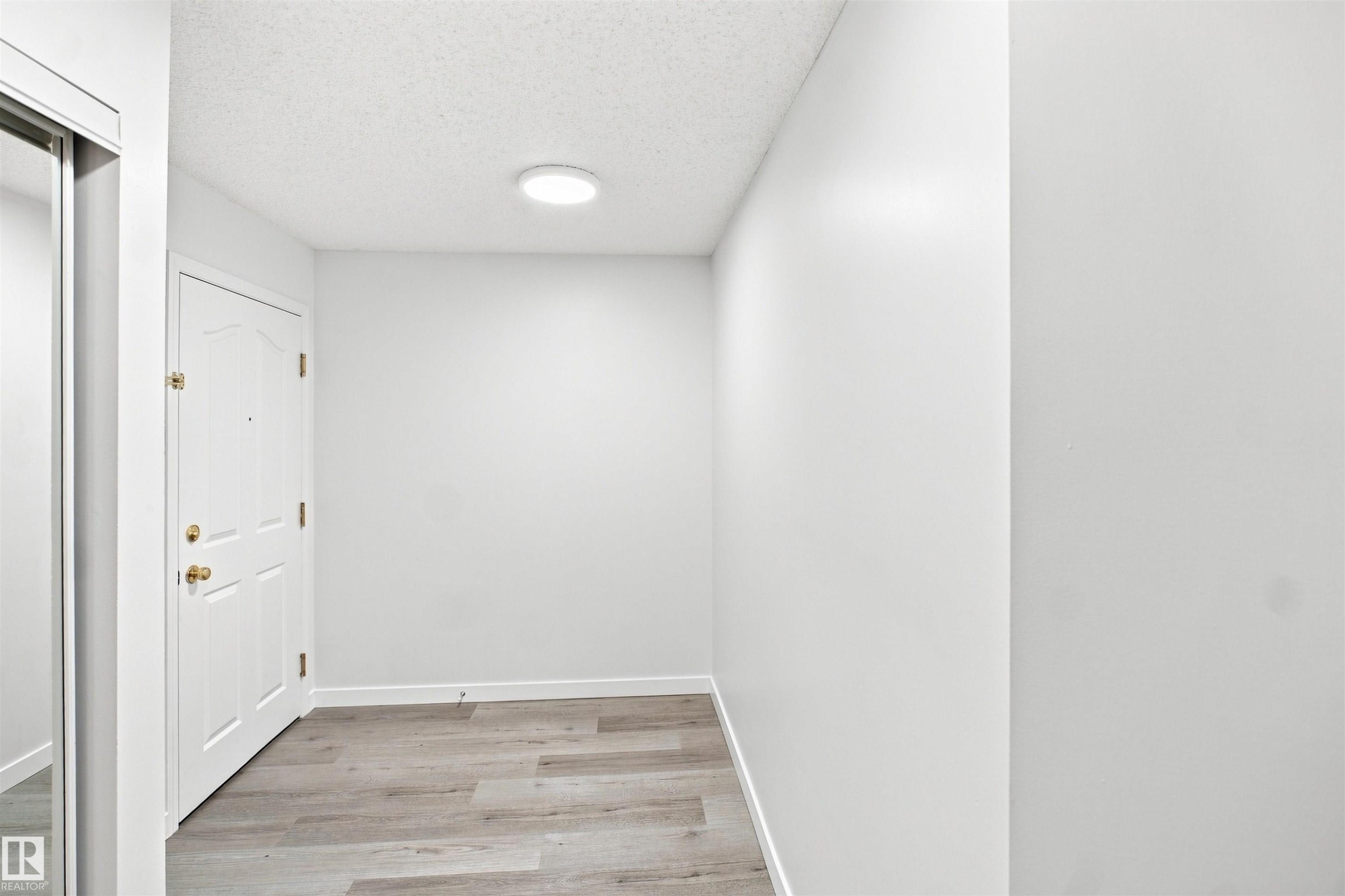 Wood-finish flooring, white walls, and a contemporary flush-mount ceiling light - #124 10511 42 Av Nw, Edmonton, AB