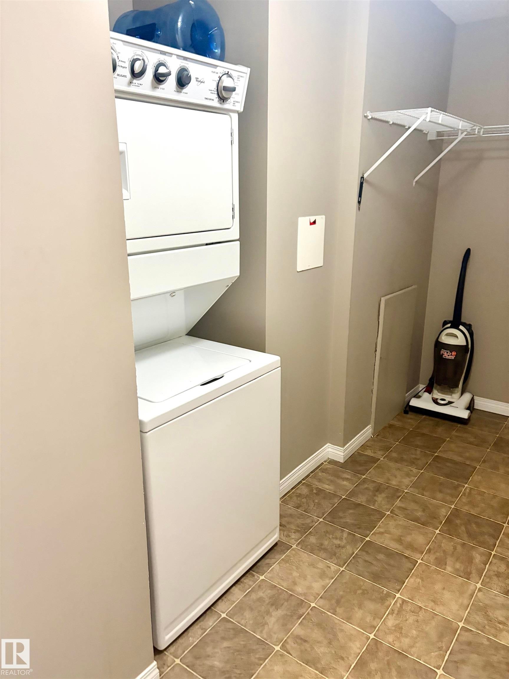 Stacked washer and dryer unit, tiled flooring, and wire shelving - #1304 9363 Simpson Dr Nw, Edmonton, AB