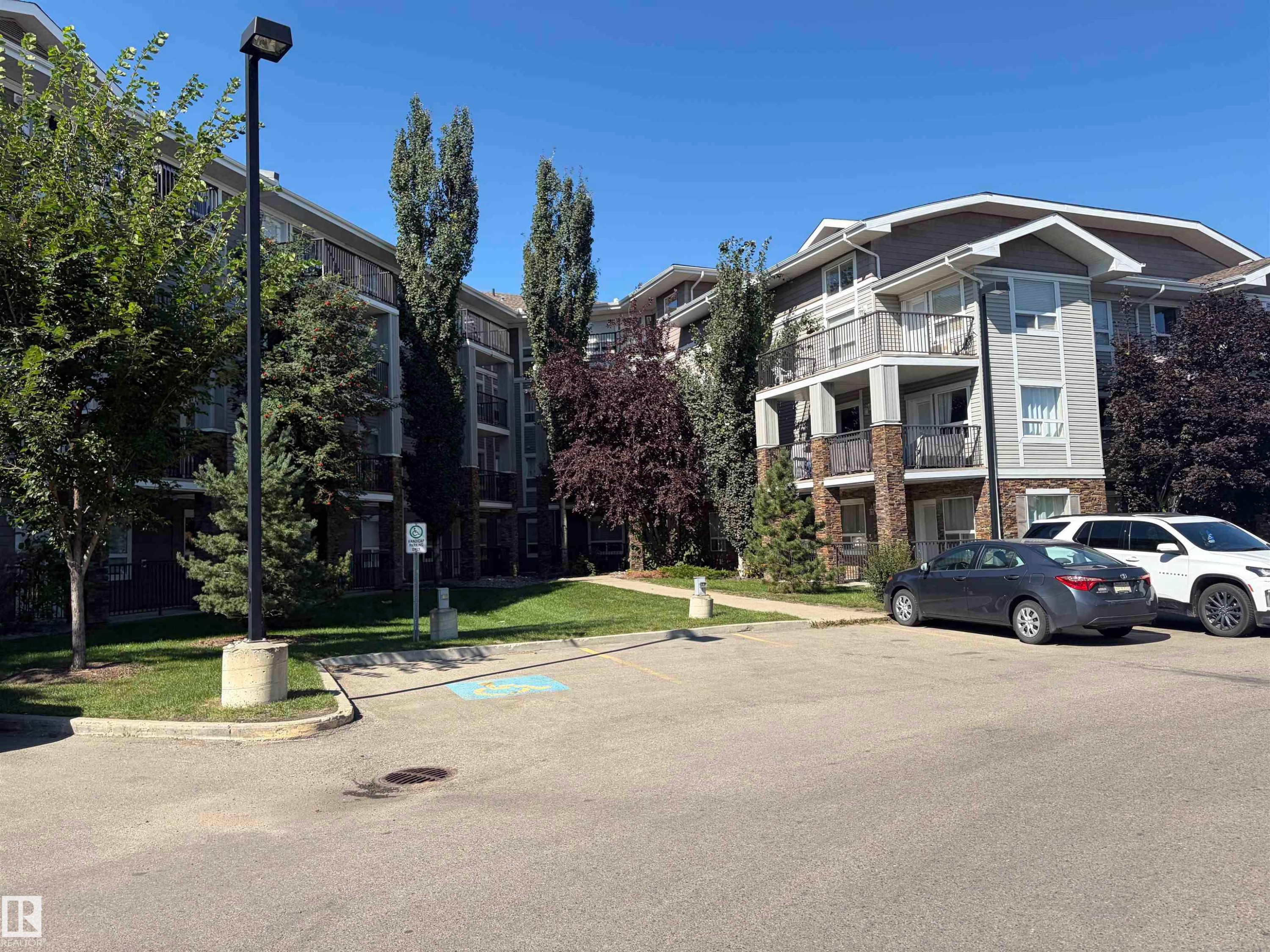 Exterior features include light gray siding, stone accents, and private balconies - #1304 9363 Simpson Dr Nw, Edmonton, AB