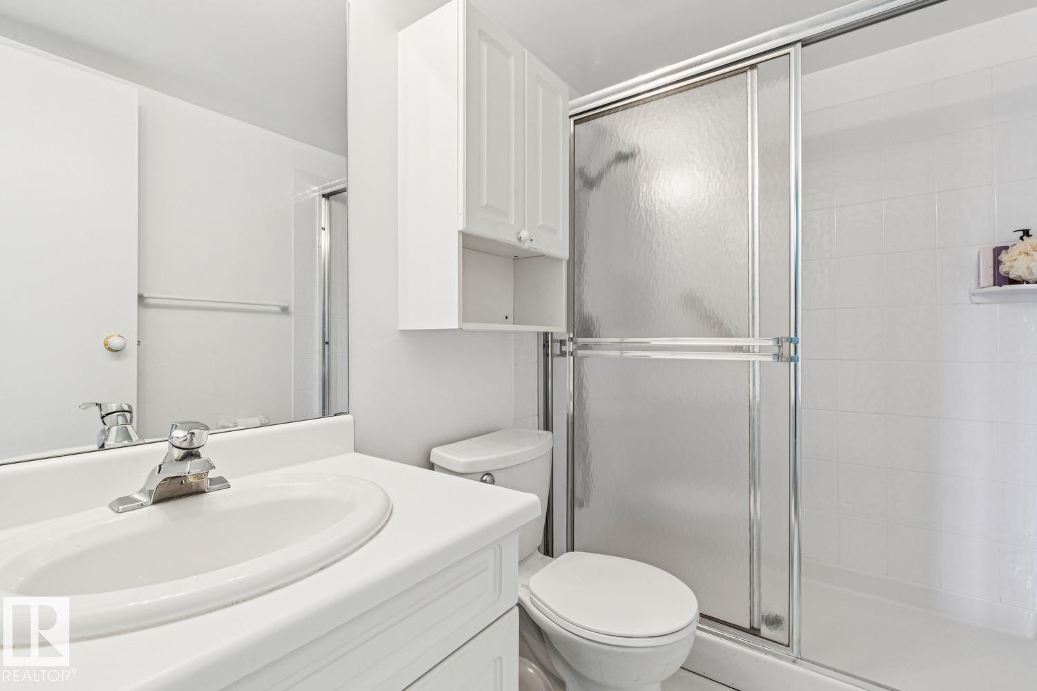 Bathroom featuring a single vanity, a chrome faucet, a wall-mounted medicine cabinet, and a shower with sliding glass doors - #905 9929 113 St Nw, Edmonton, AB