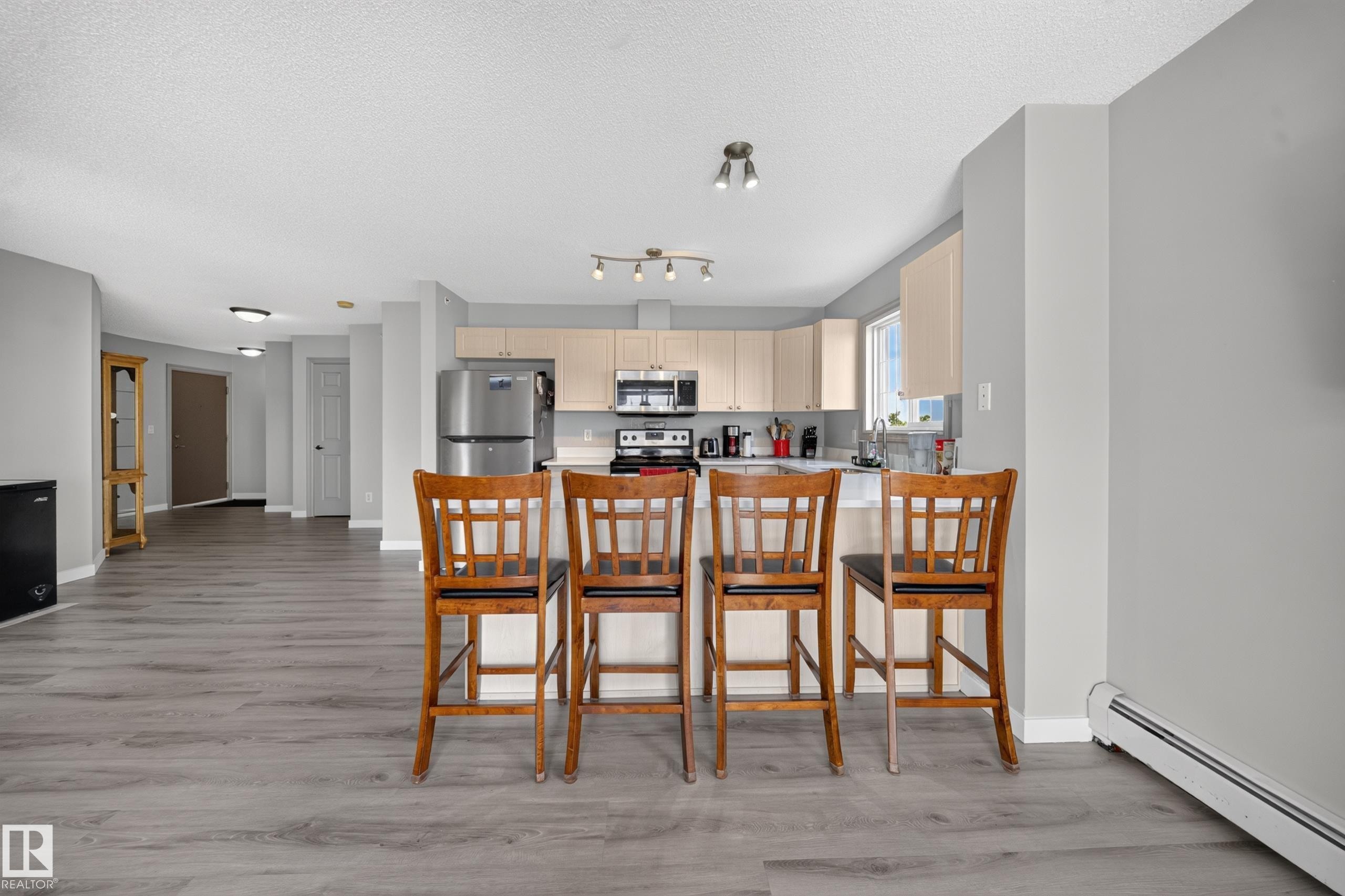 Kitchen with light wood-finish cabinetry, stainless steel appliances, and a breakfast bar - #419 4407 23 St Nw, Edmonton, AB