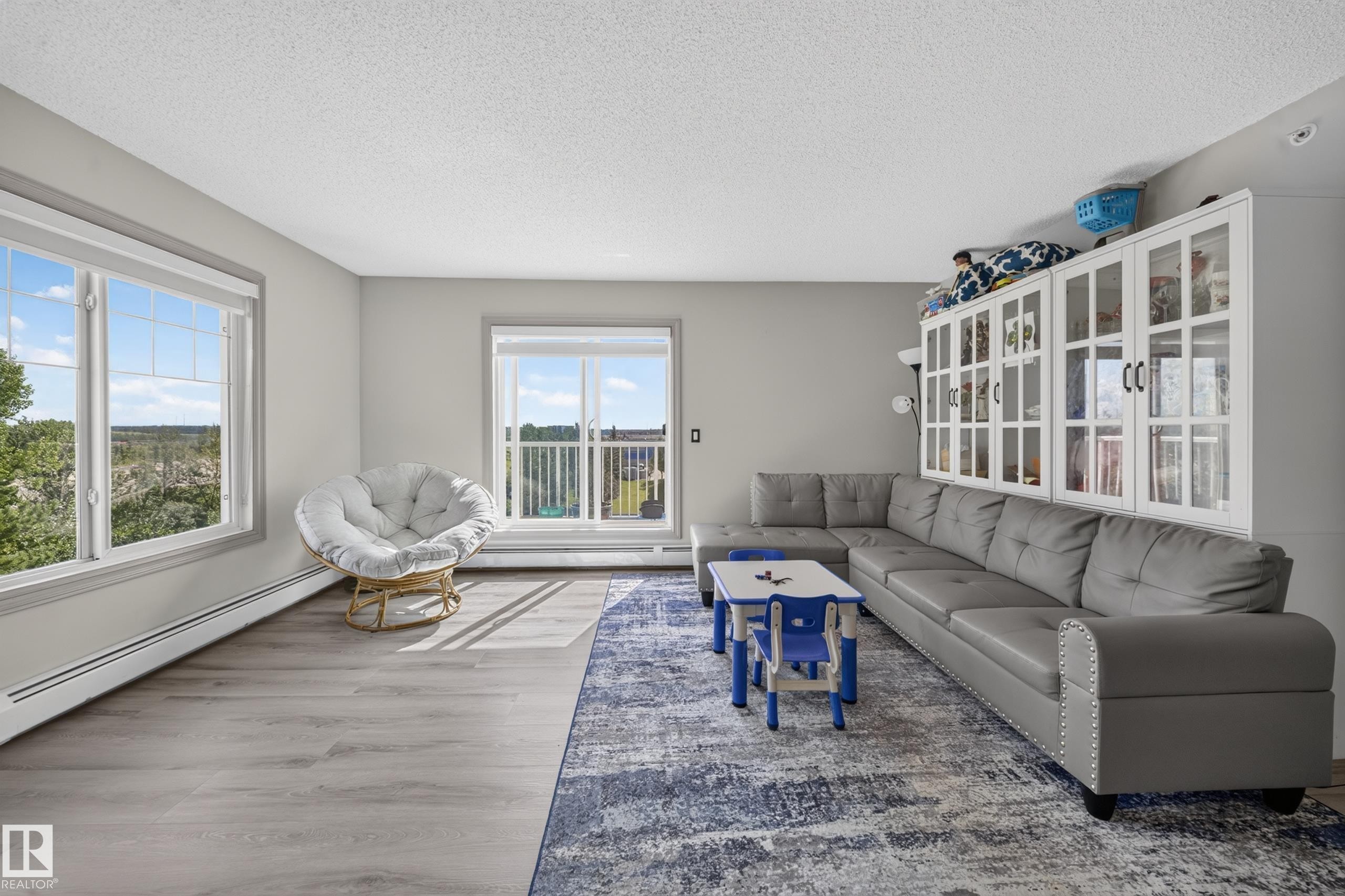 Light gray wood-finish flooring with white baseboard heating - #419 4407 23 St Nw, Edmonton, AB
