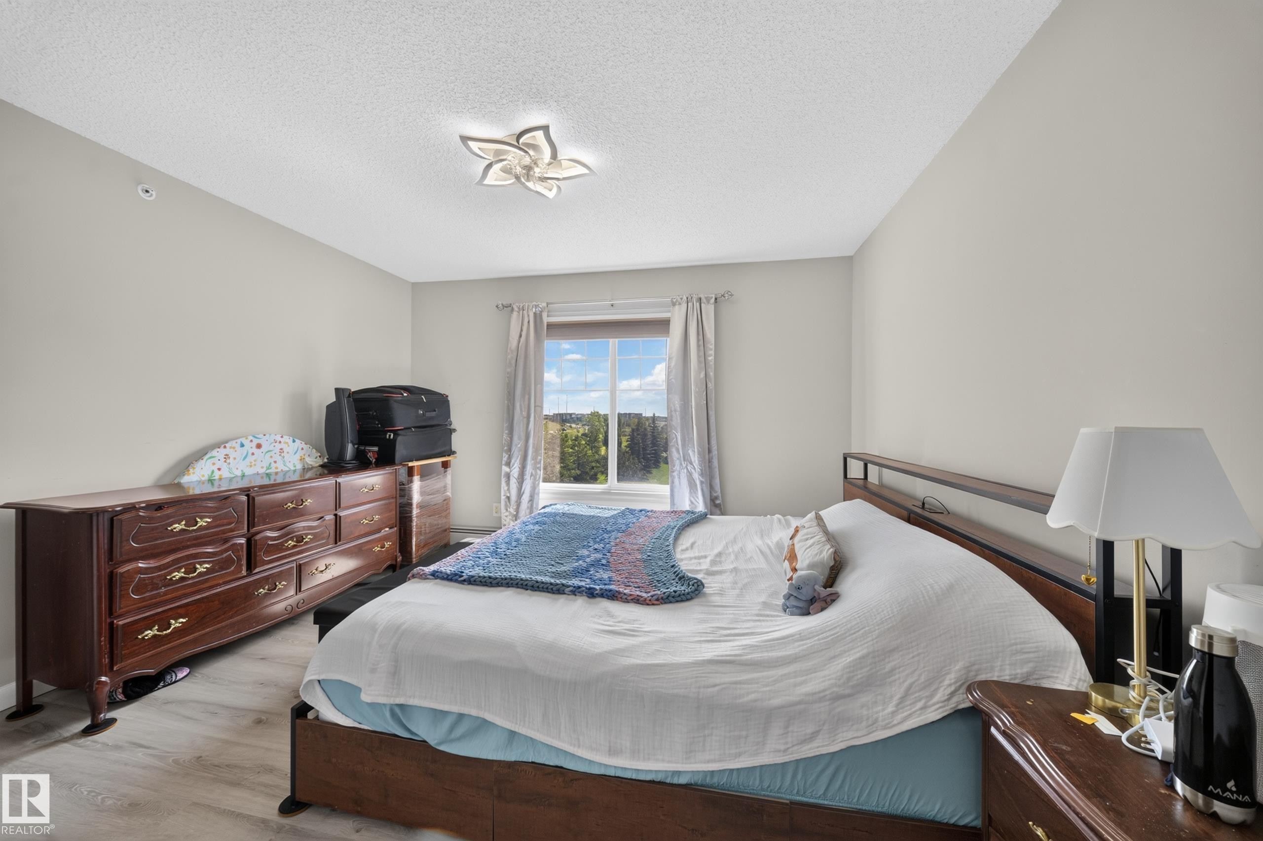 Recessed window with drapes, wood-finish flooring, and a unique ceiling light fixture - #419 4407 23 St Nw, Edmonton, AB