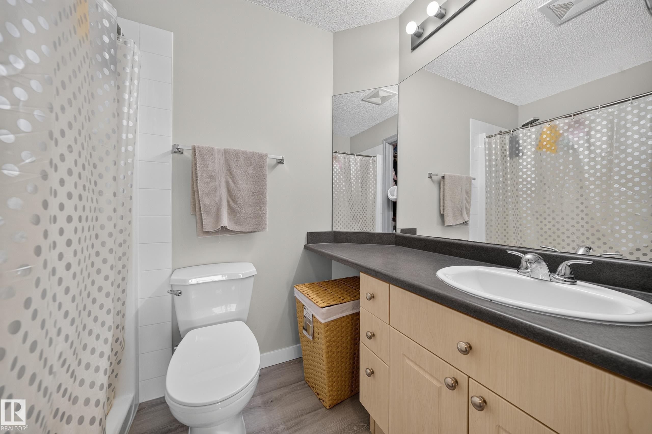Wood-finish flooring, light tone cabinetry with brushed nickel hardware, and dark countertop with integrated sink - #419 4407 23 St Nw, Edmonton, AB