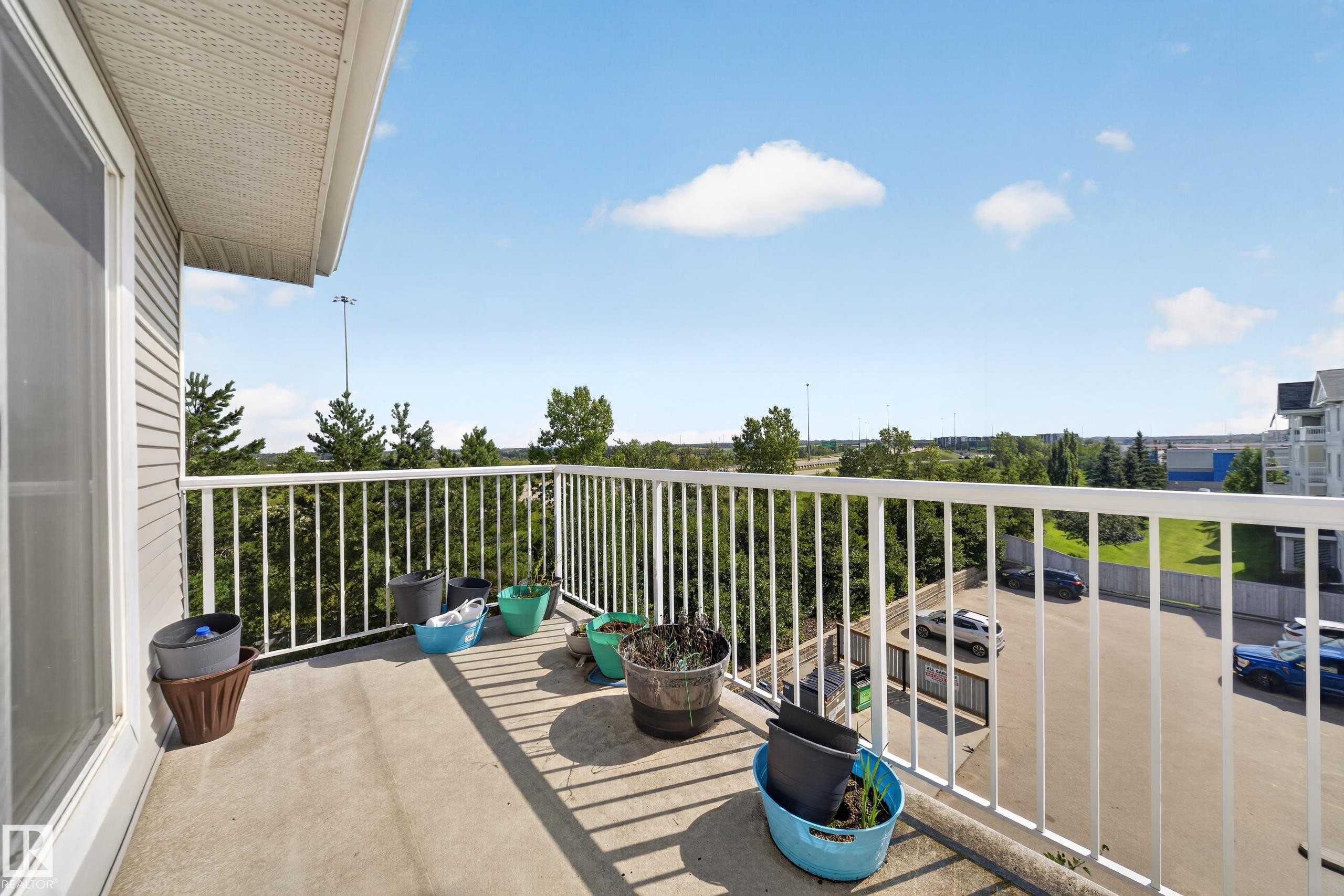 Concrete balcony with white metal railing and a sliding glass door - #419 4407 23 St Nw, Edmonton, AB