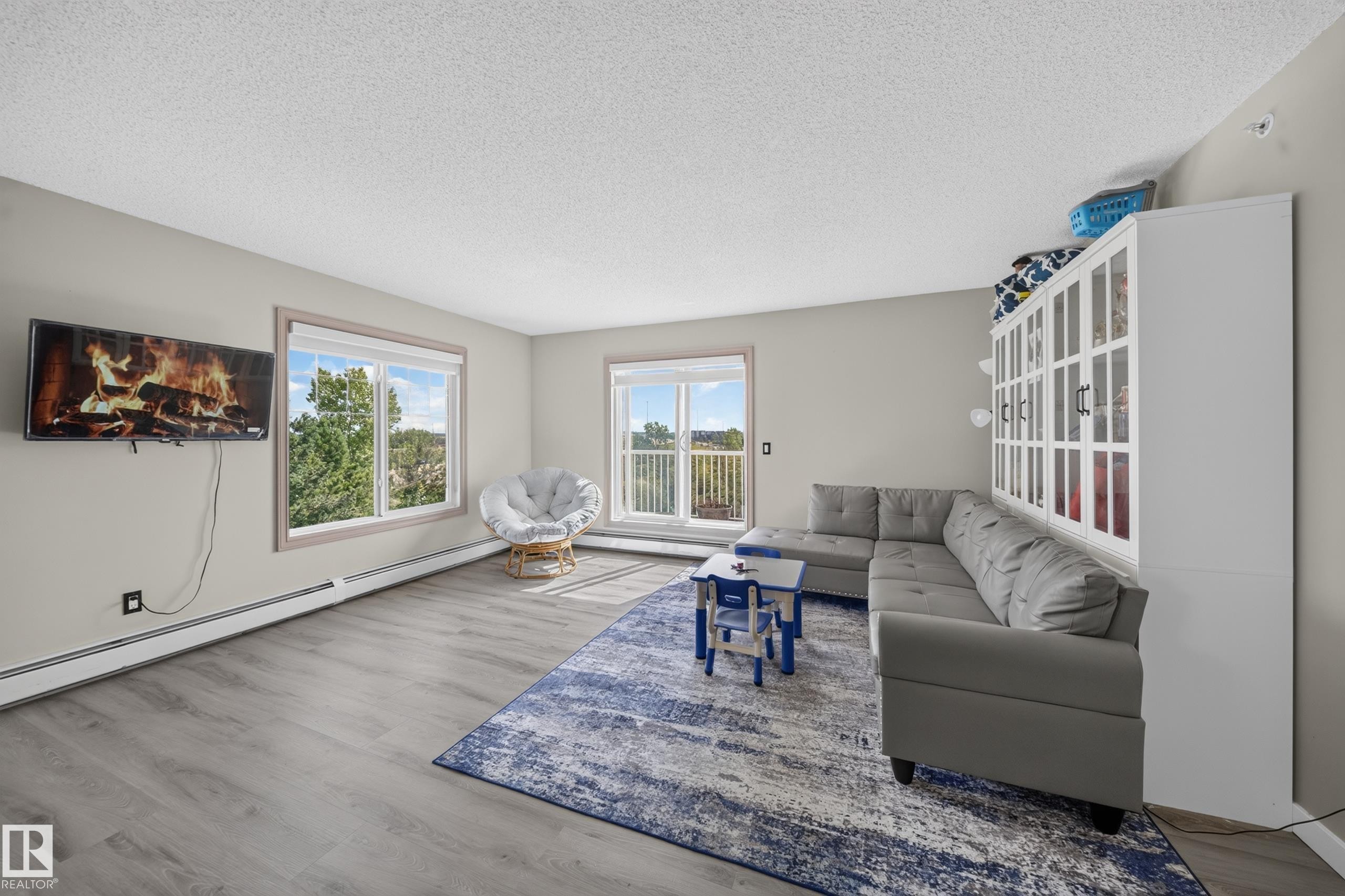 Wood-finish flooring, light grey wall paint, multiple windows, and a built-in display cabinet - #419 4407 23 St Nw, Edmonton, AB