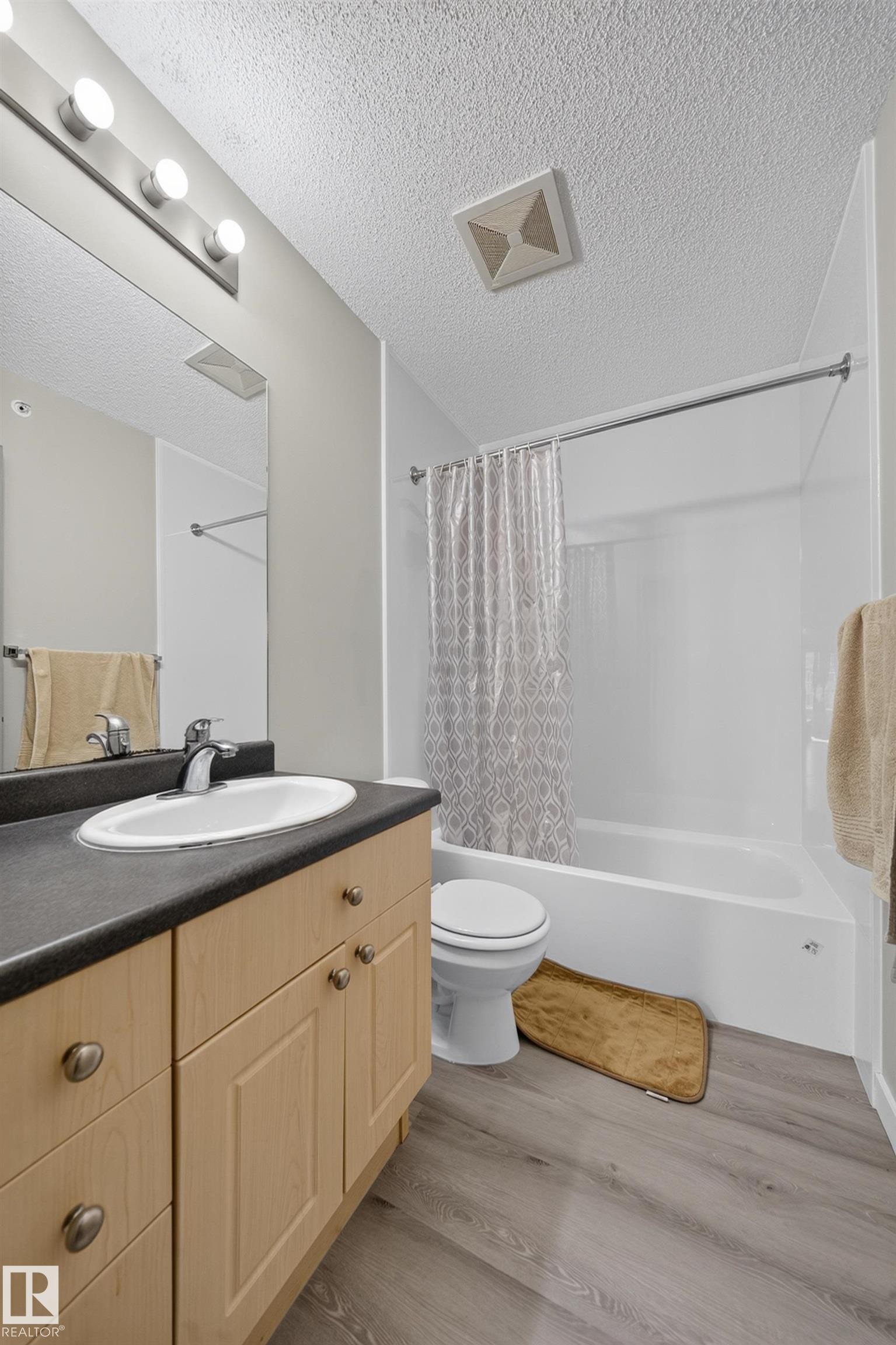 Light wood-finish vanity with a dark countertop and integrated sink - #419 4407 23 St Nw, Edmonton, AB