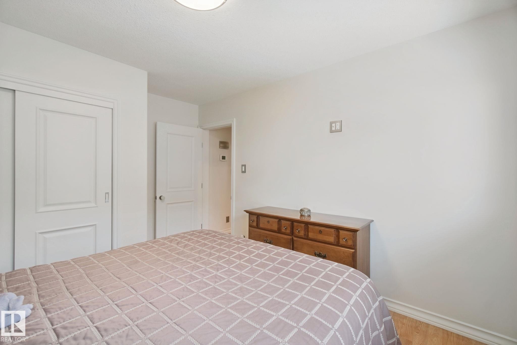 White walls, wood-finish flooring, recessed ceiling light, white paneled interior doors, and white trim - 12916 63 Street Nw, Edmonton, AB