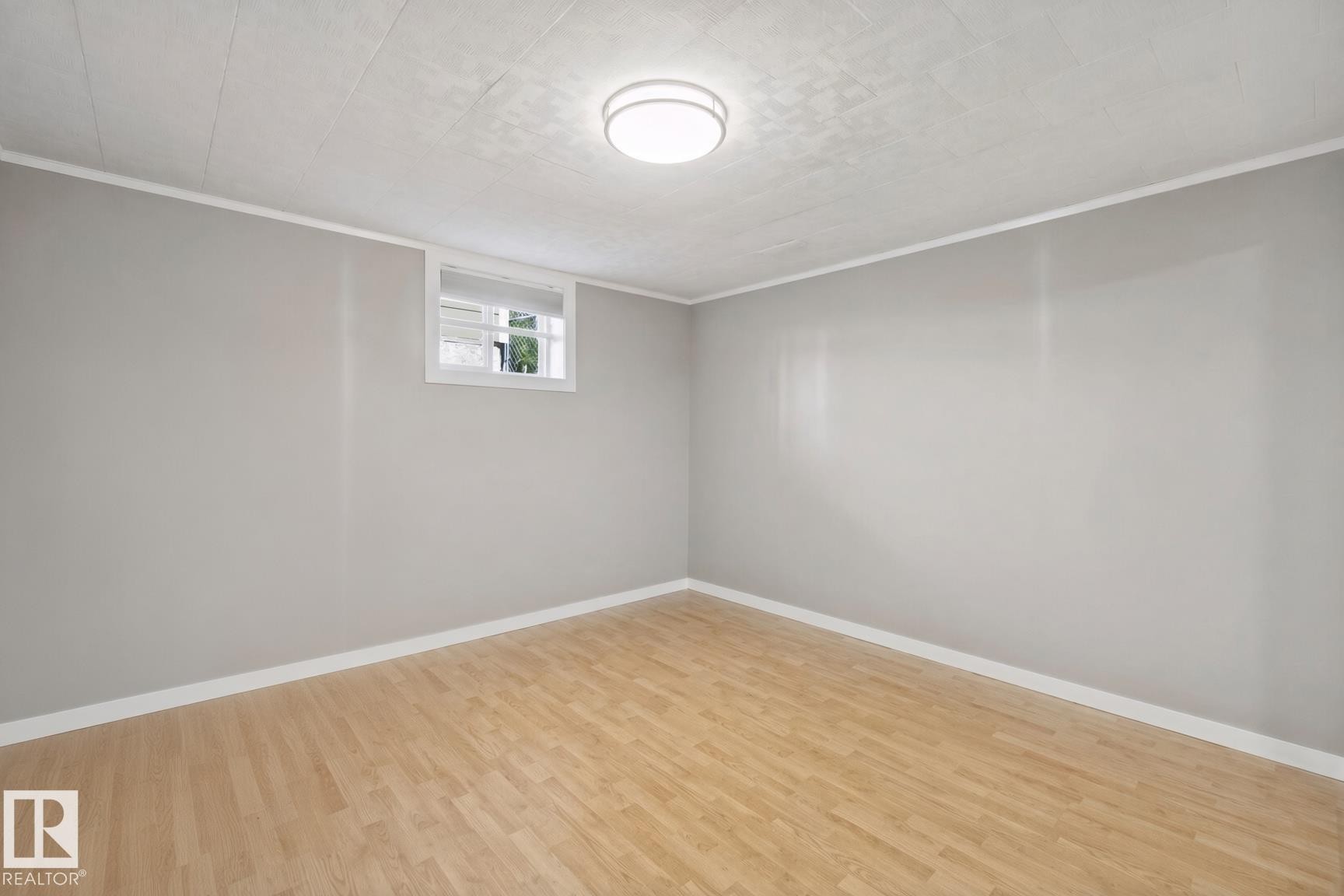 Light wood-finish flooring, neutral gray walls, white trim, and a flush-mount ceiling light - 12916 63 Street Nw, Edmonton, AB