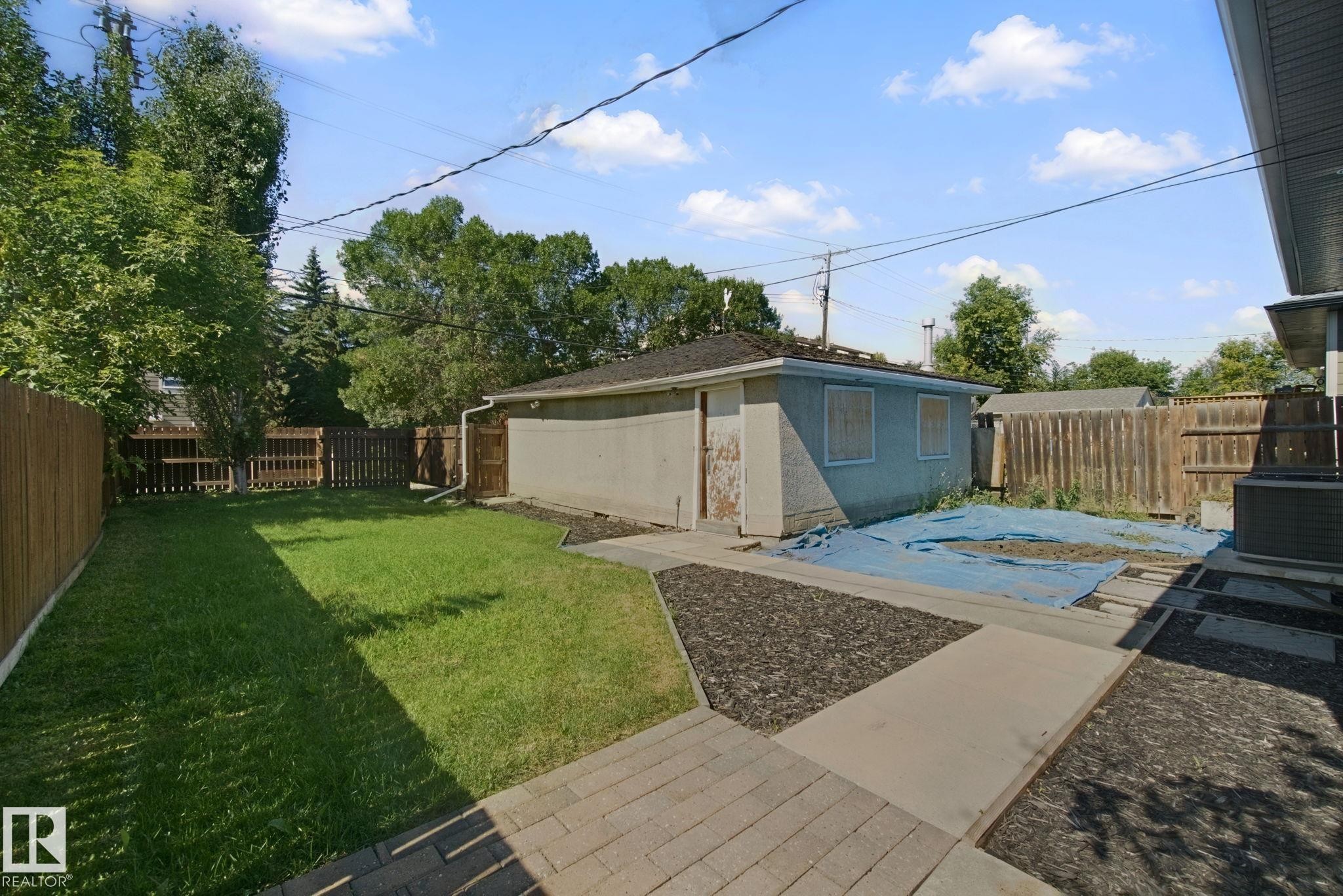 Private backyard featuring a fenced perimeter, a concrete patio, and a manicured lawn - 12916 63 Street Nw, Edmonton, AB