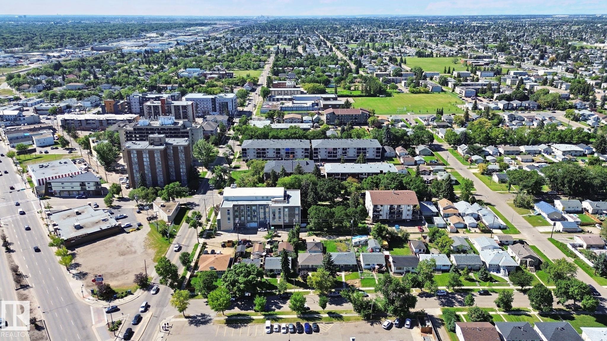 Expansive urban landscape featuring mature trees, diverse residential architecture, multistory commercial buildings, and surface parking areas - 12916 63 Street Nw, Edmonton, AB