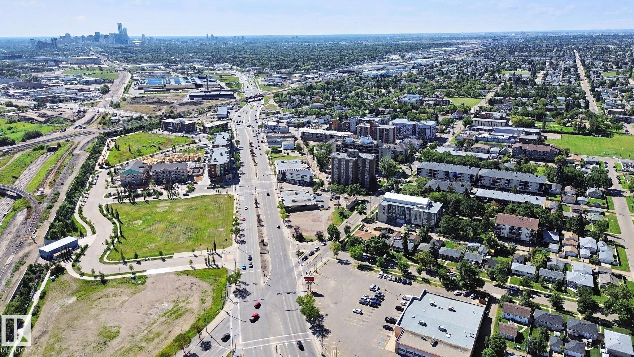Urban landscape with extensive green spaces, a prominent central thoroughfare, and a distant city skyline - 12916 63 Street Nw, Edmonton, AB