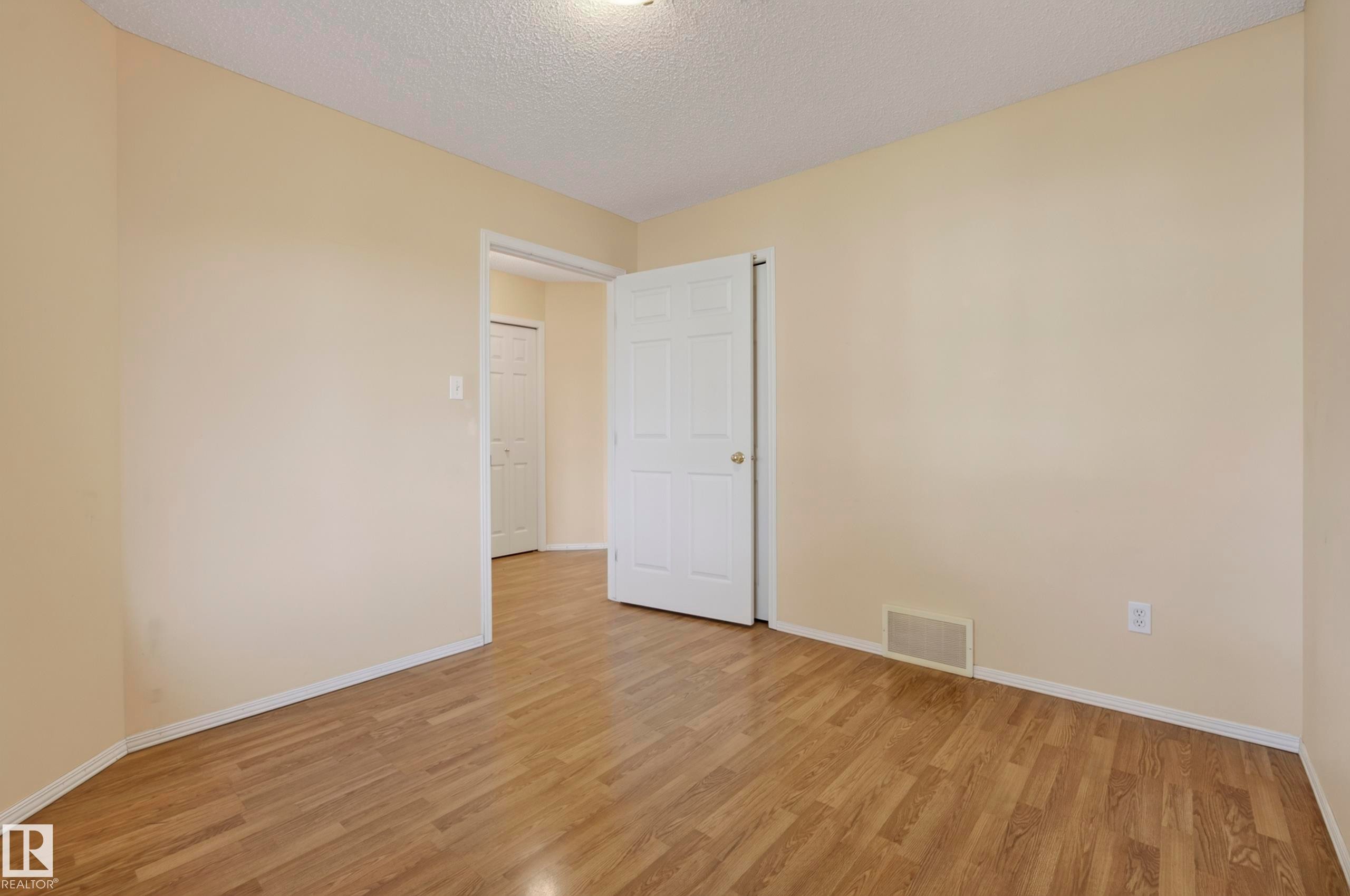 Wood-finish flooring throughout, neutral wall paint, and white trim - 15213 49A Street Nw, Edmonton, AB