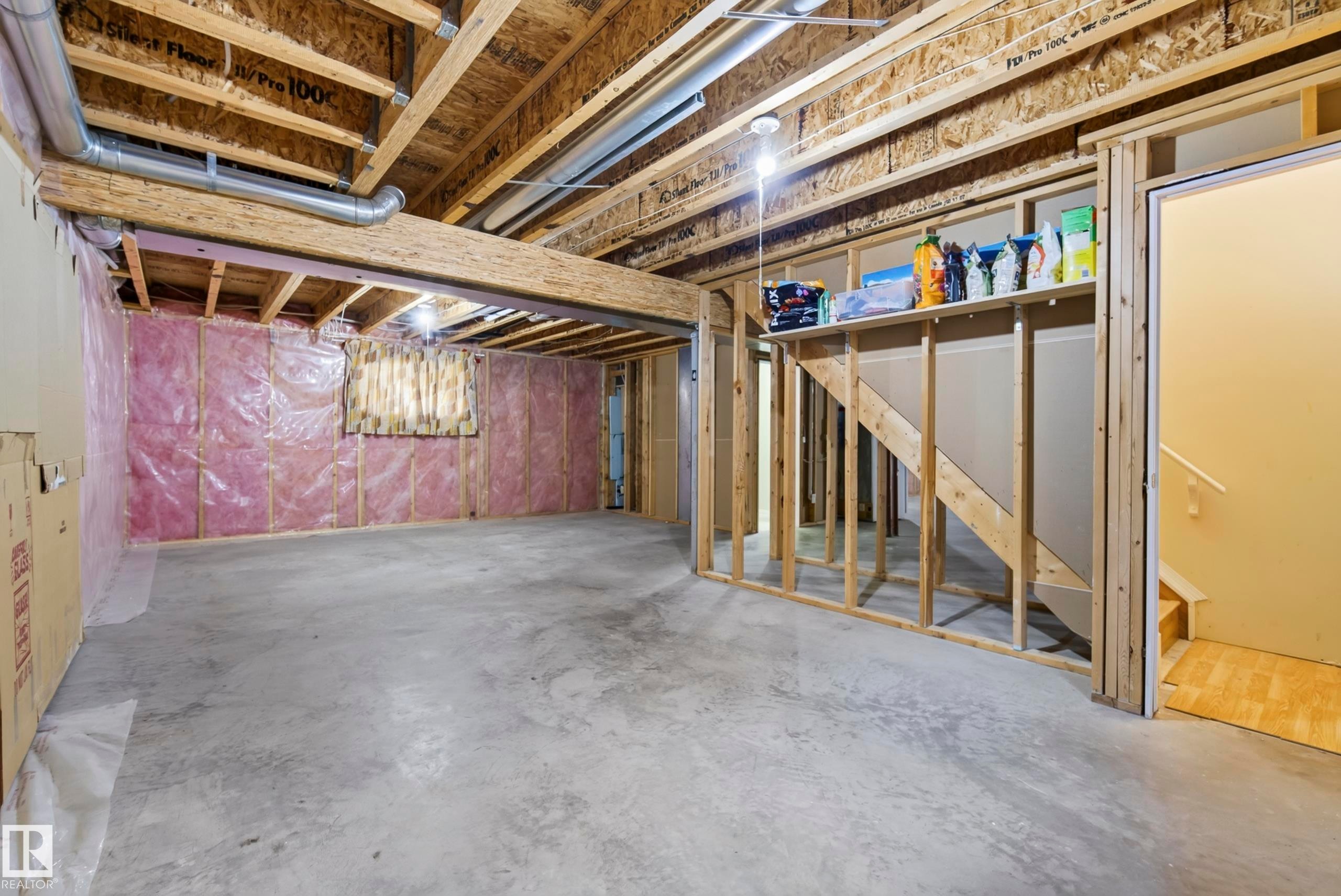 Unfinished basement with concrete flooring, exposed wood framing, and visible insulation - 15213 49A Street Nw, Edmonton, AB