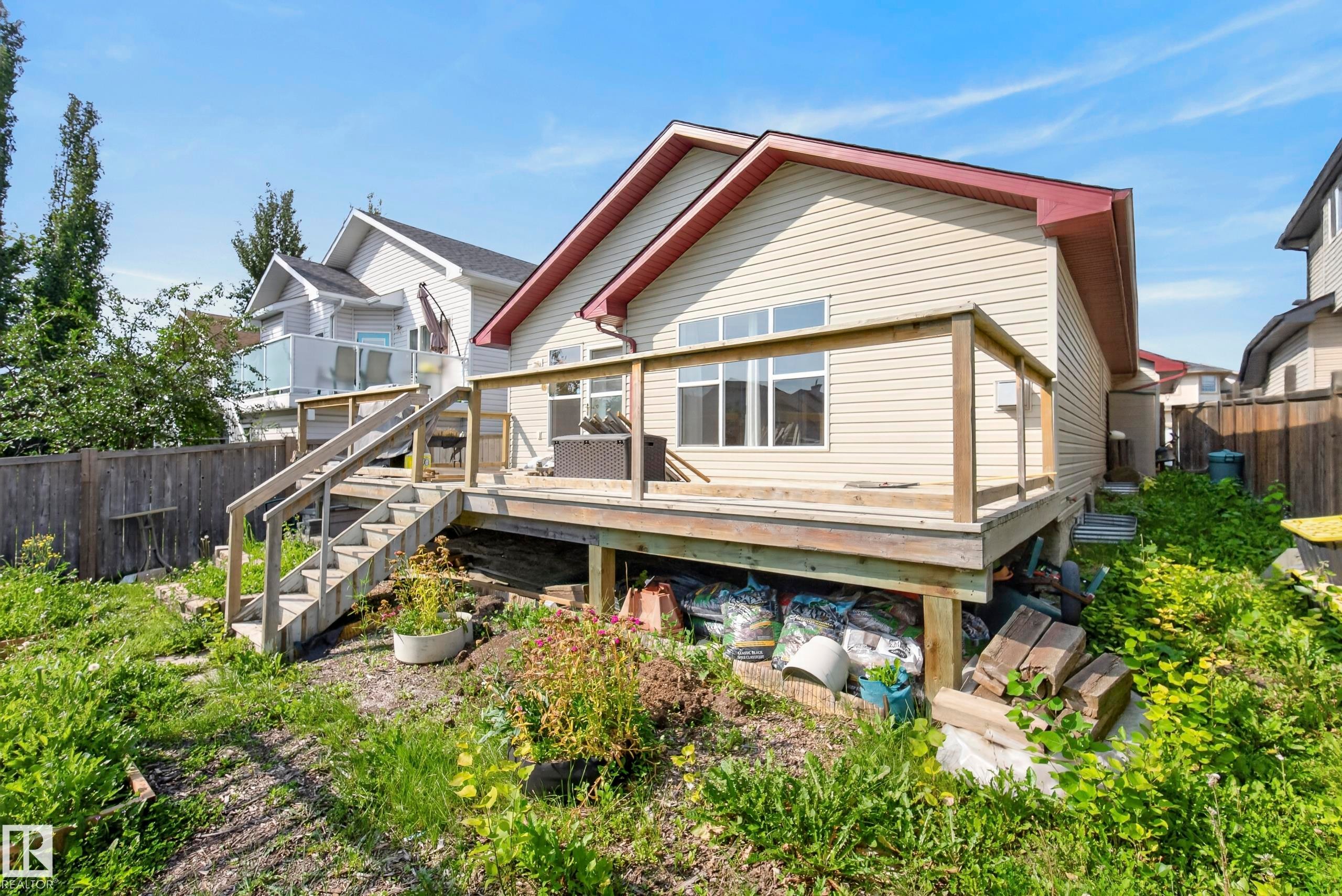 Expansive rear deck with wood railing, featuring direct yard access via stairs - 15213 49A Street Nw, Edmonton, AB