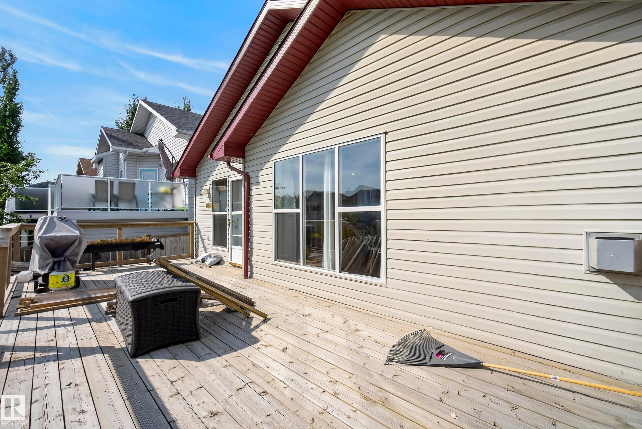 Spacious wooden deck with railing, siding exterior, and multiple windows - 15213 49A Street Nw, Edmonton, AB