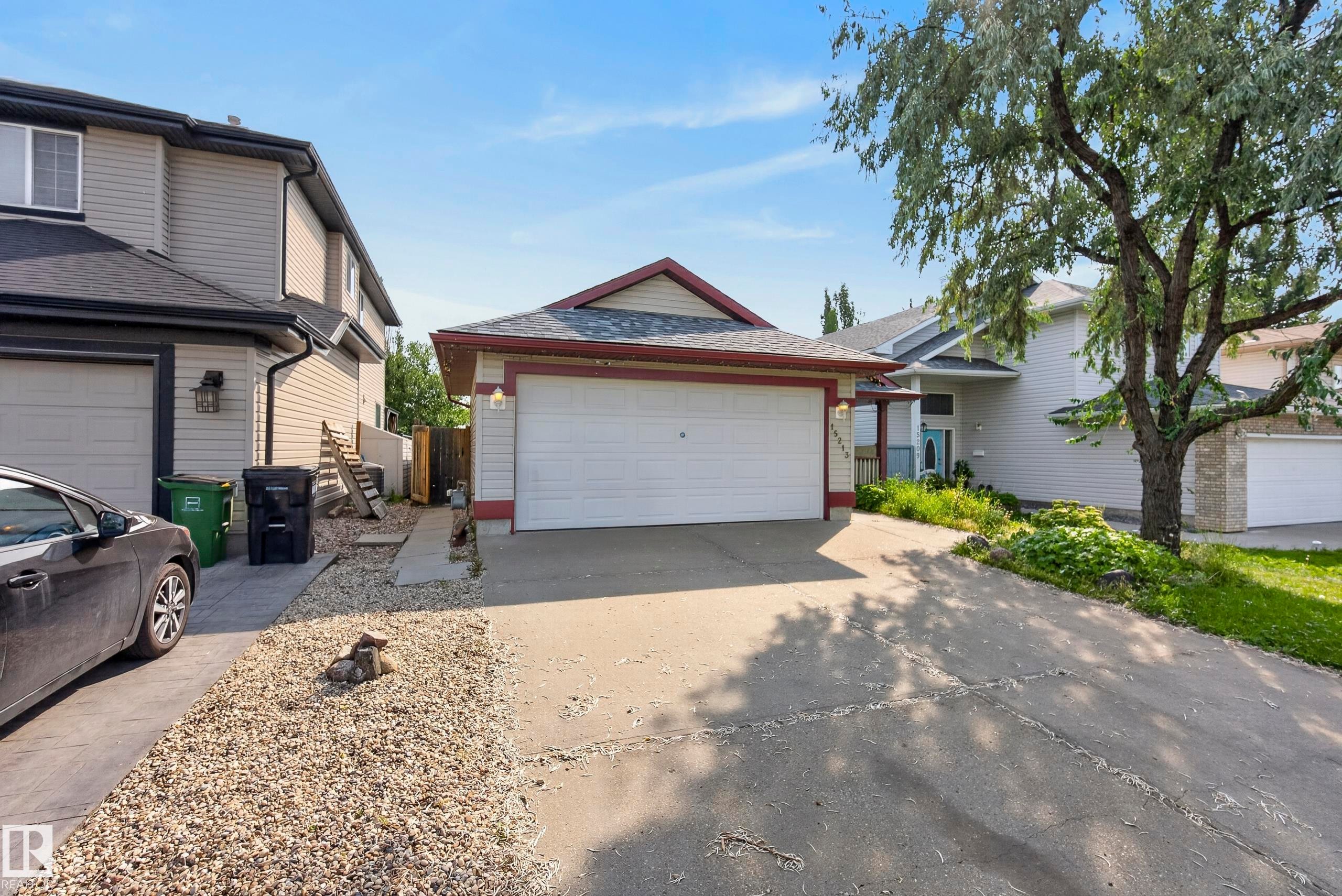 Single-family dwelling featuring an attached two-car garage, concrete driveway, and gravel landscaping - 15213 49A Street Nw, Edmonton, AB