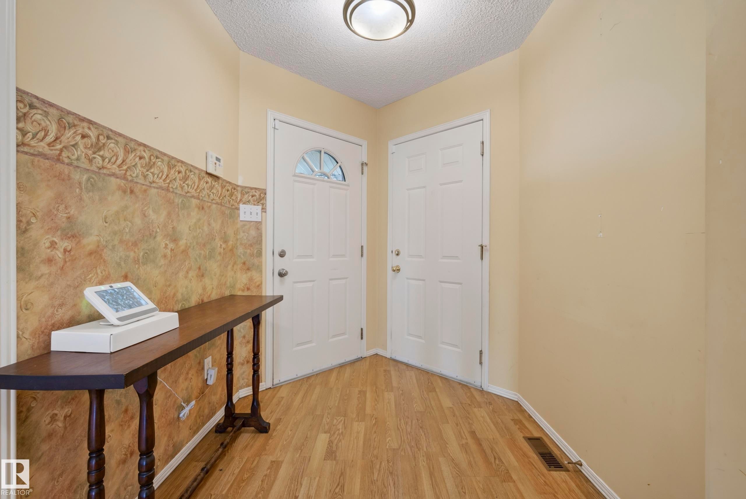 Wood-finish flooring with a textured wall treatment and dual paneled doors - 15213 49A Street Nw, Edmonton, AB