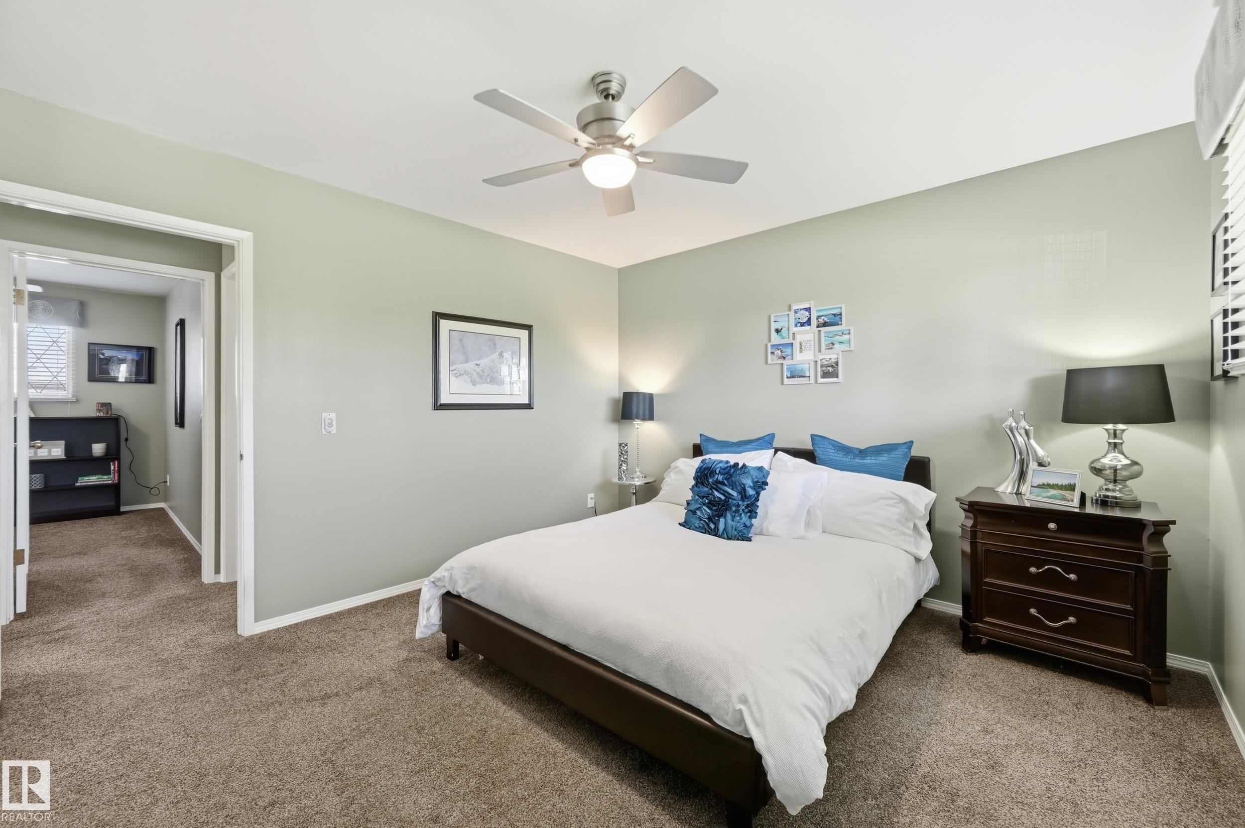 Spacious primary bedroom featuring soft sage-green walls, carpeted flooring, and abundant natural light from multiple windows - 10552 45 Street Nw, Edmonton, AB