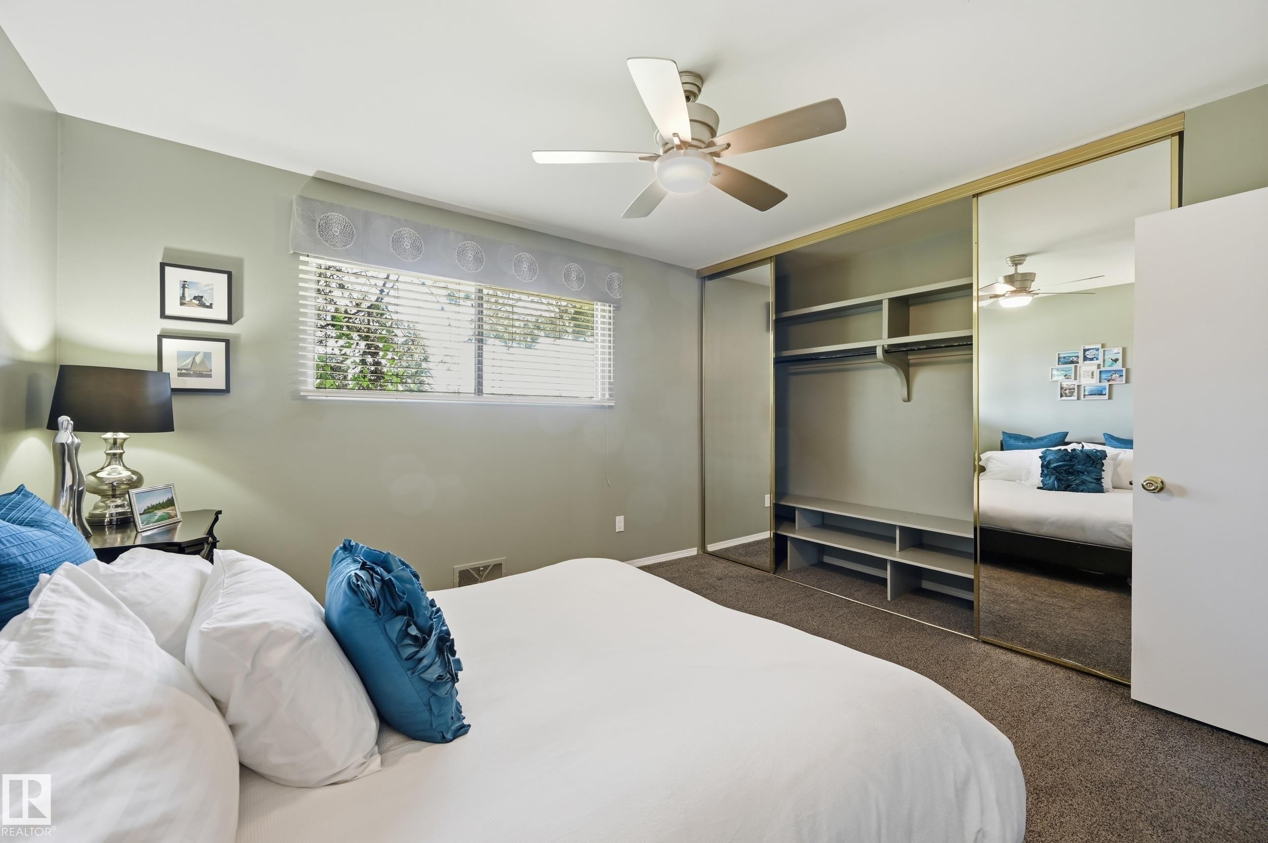 Built-in shelving, carpet flooring, ceiling fan, mirrored closet doors, and window with blinds - 10552 45 Street Nw, Edmonton, AB