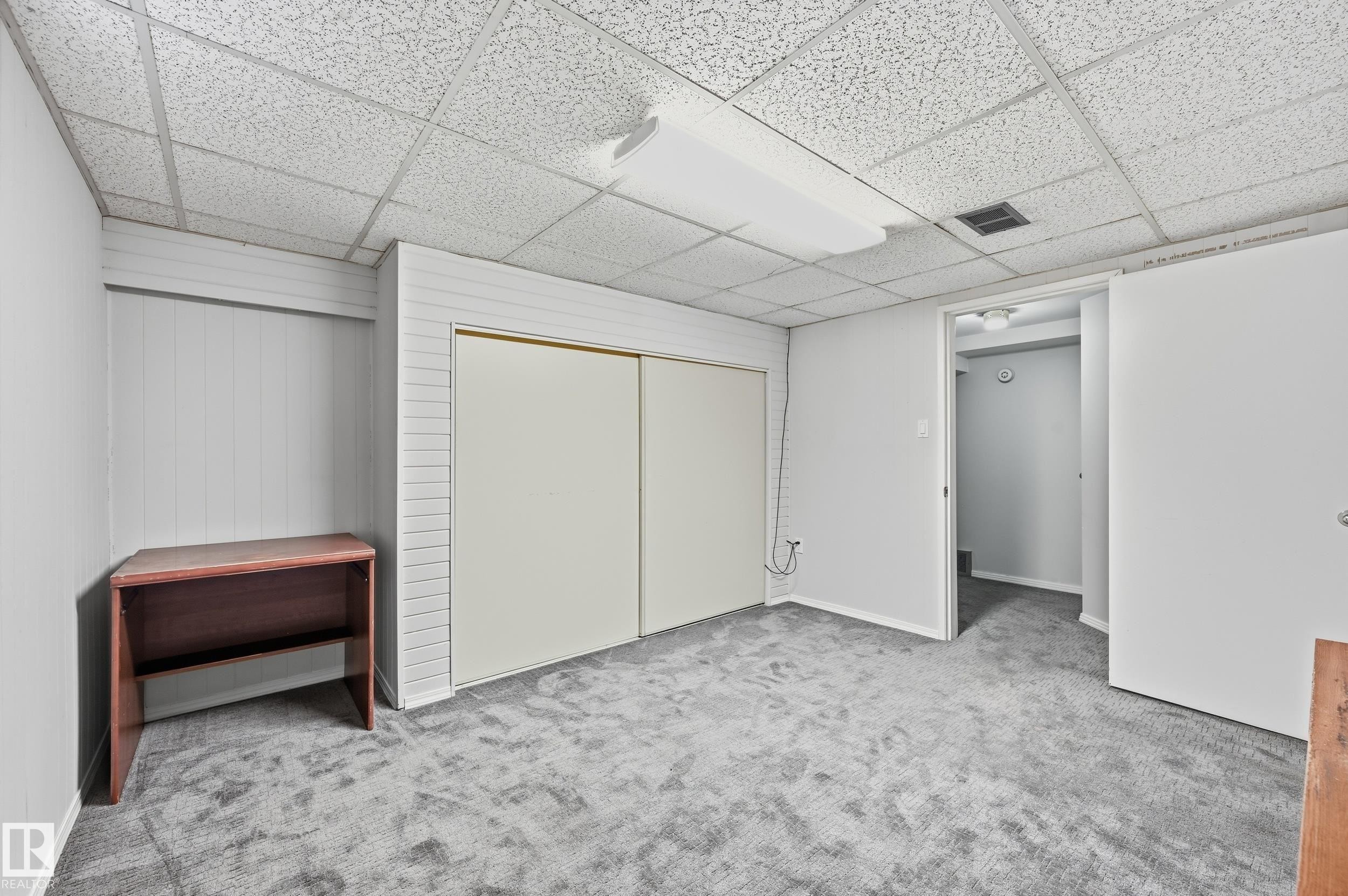 Textured drop ceiling with fluorescent lighting, light gray walls, and gray carpeted flooring - 10552 45 Street Nw, Edmonton, AB