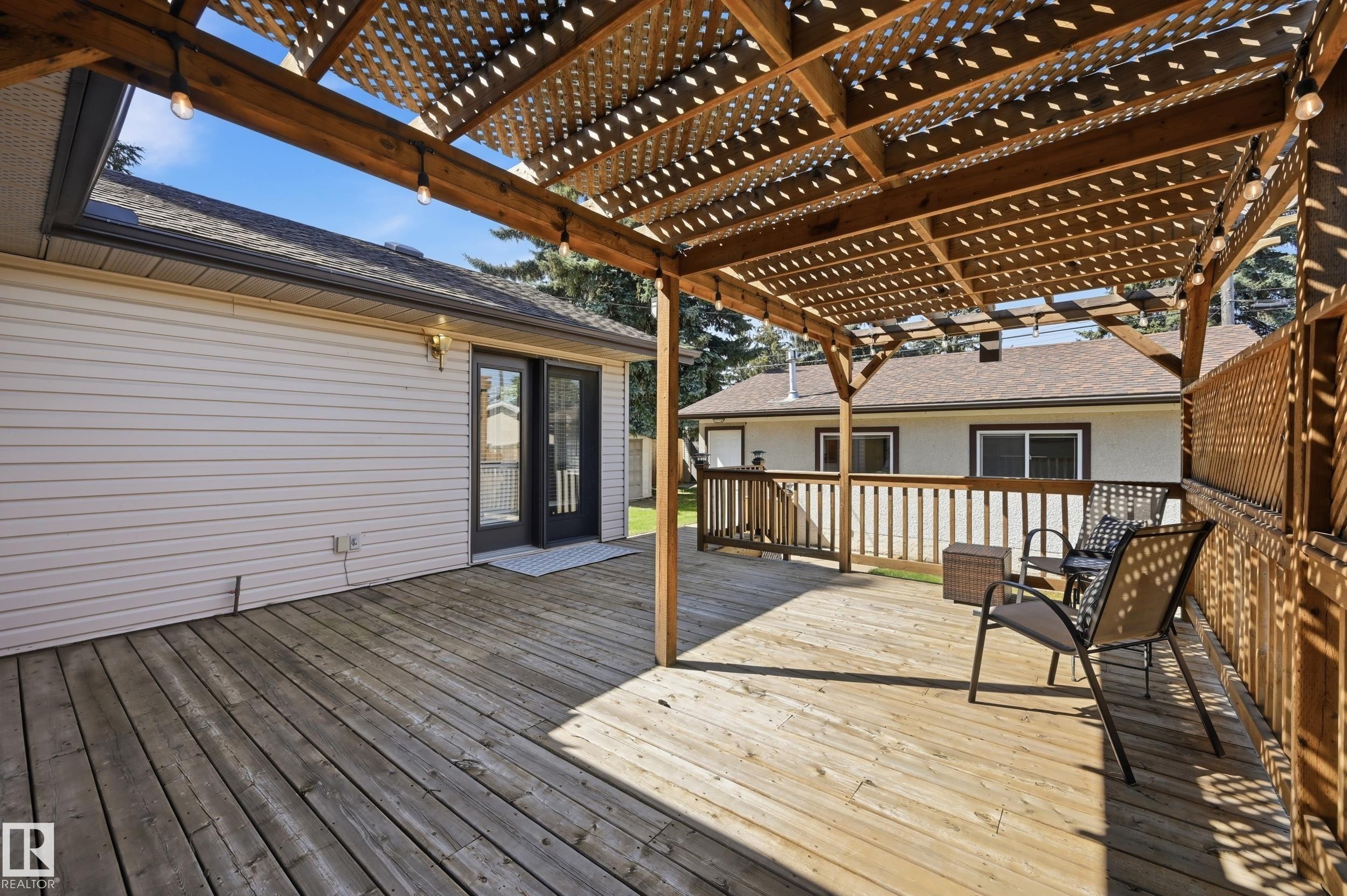 Wood-finish deck with a lattice pergola, dual pane French doors, and exterior lighting - 10552 45 Street Nw, Edmonton, AB