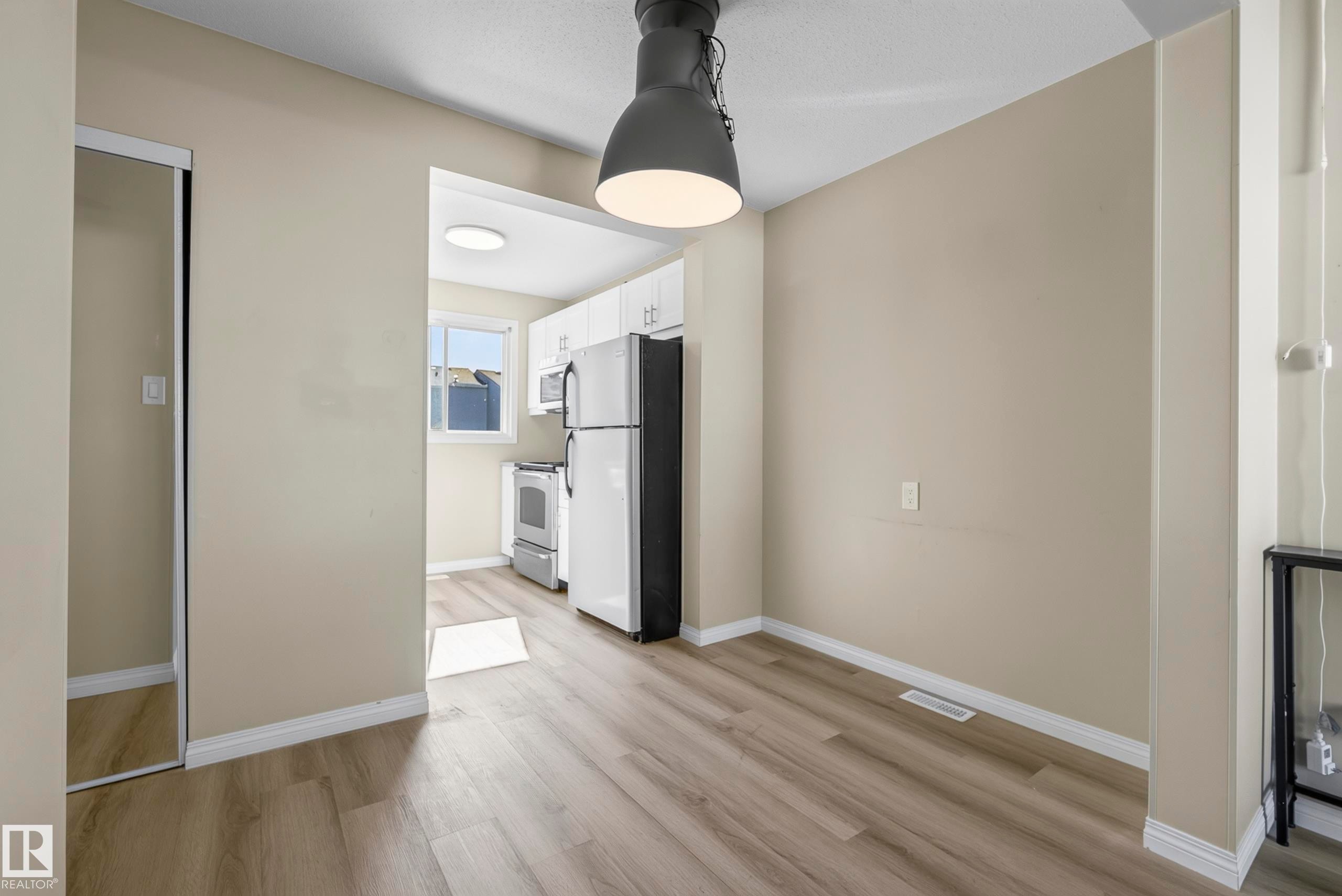 Wood-finish flooring throughout, complemented by light-toned wall paint - 141 Dickinsfield Court Nw, Edmonton, AB