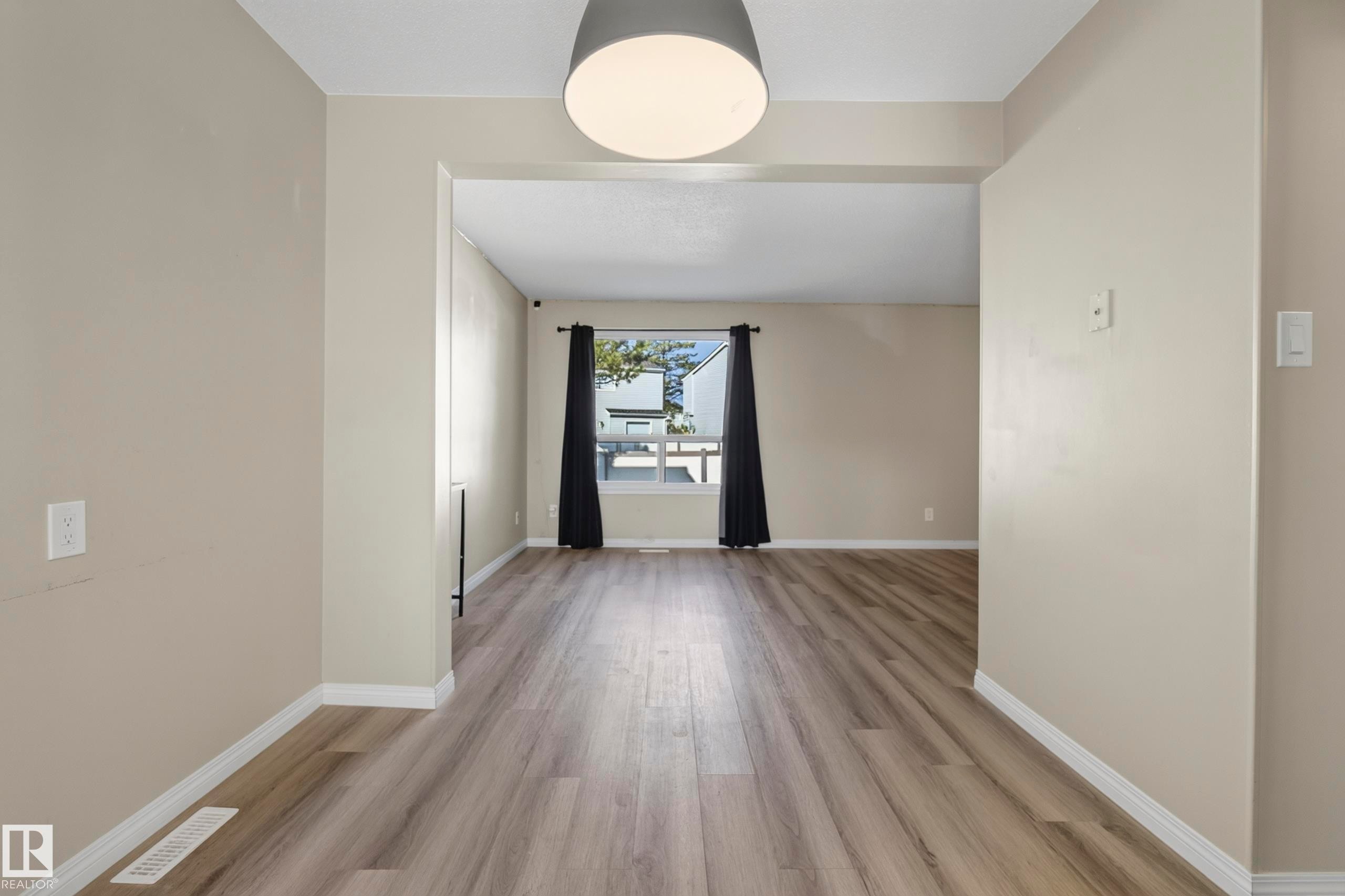 Spacious interior with wood-finish flooring, neutral paint, and an open doorway - 141 Dickinsfield Court Nw, Edmonton, AB