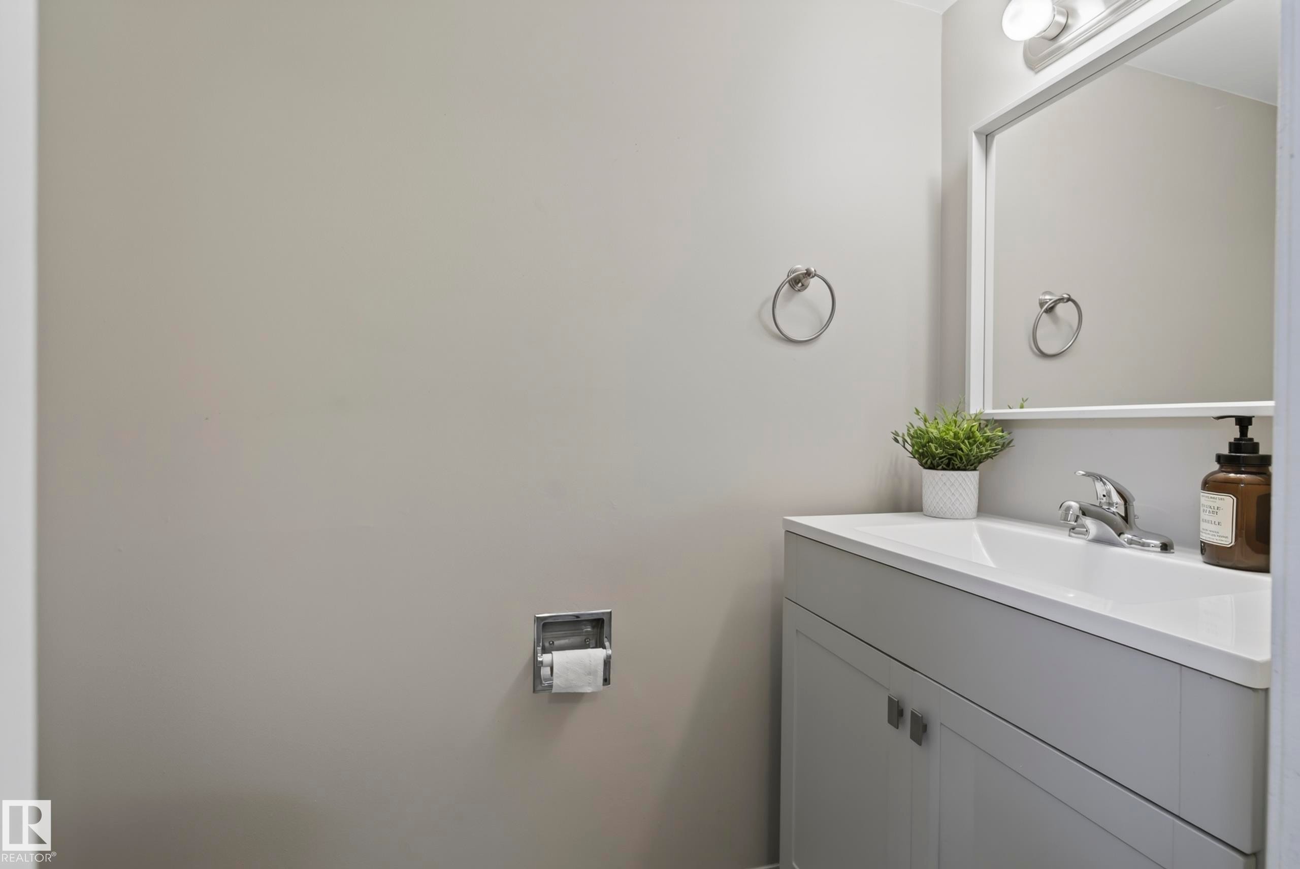 Vanity with integrated sink, chrome faucet, wall-mounted mirror, and overhead lighting fixture - 141 Dickinsfield Court Nw, Edmonton, AB