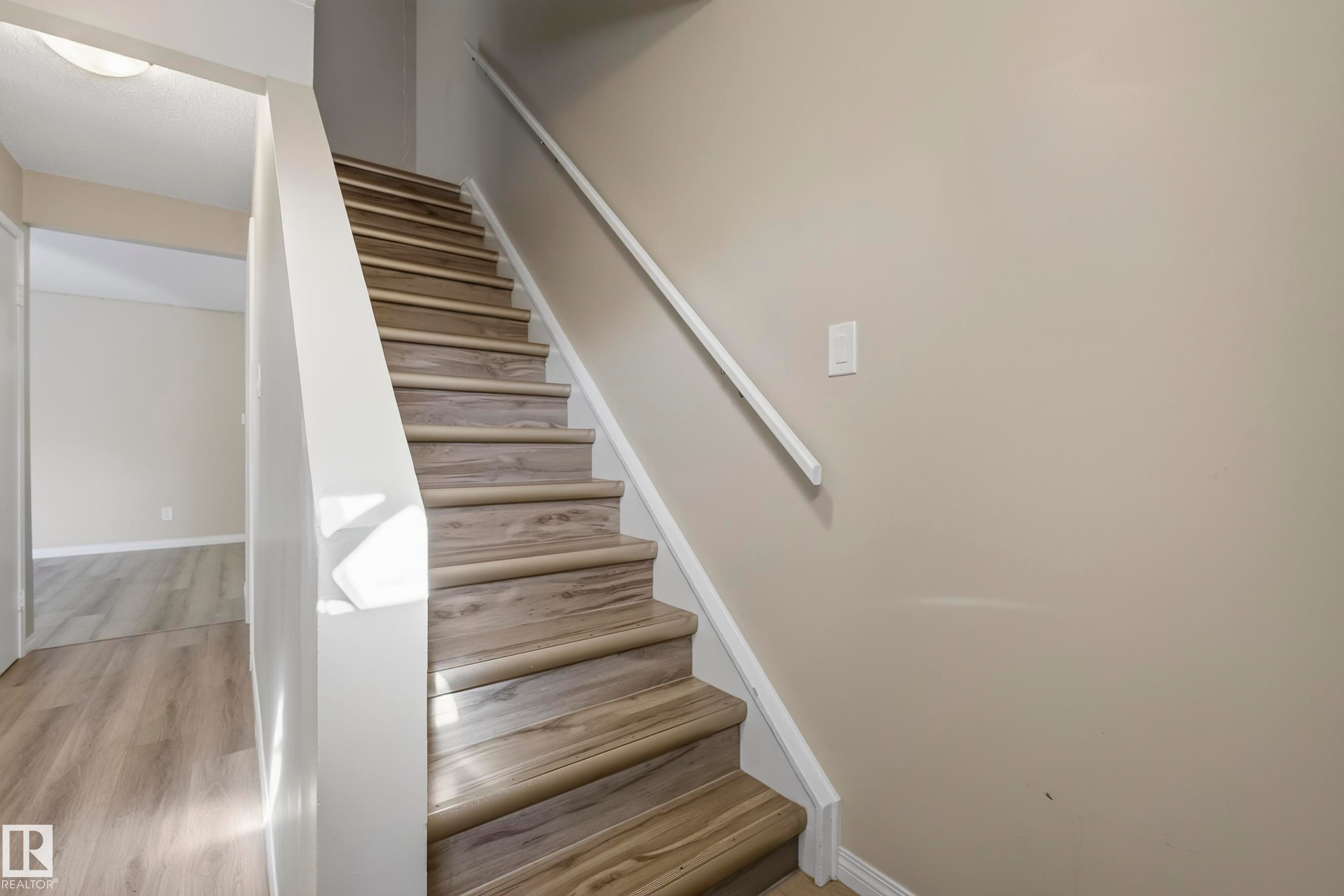 Staircase featuring wood-finish treads and risers, white handrail, and neutral wall paint - 141 Dickinsfield Court Nw, Edmonton, AB