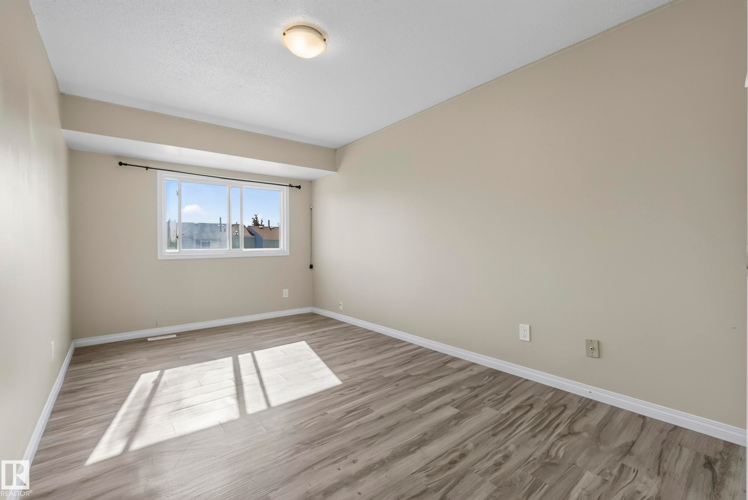 Light-toned walls, wood-finish flooring, and a ceiling-mounted light fixture - 141 Dickinsfield Court Nw, Edmonton, AB