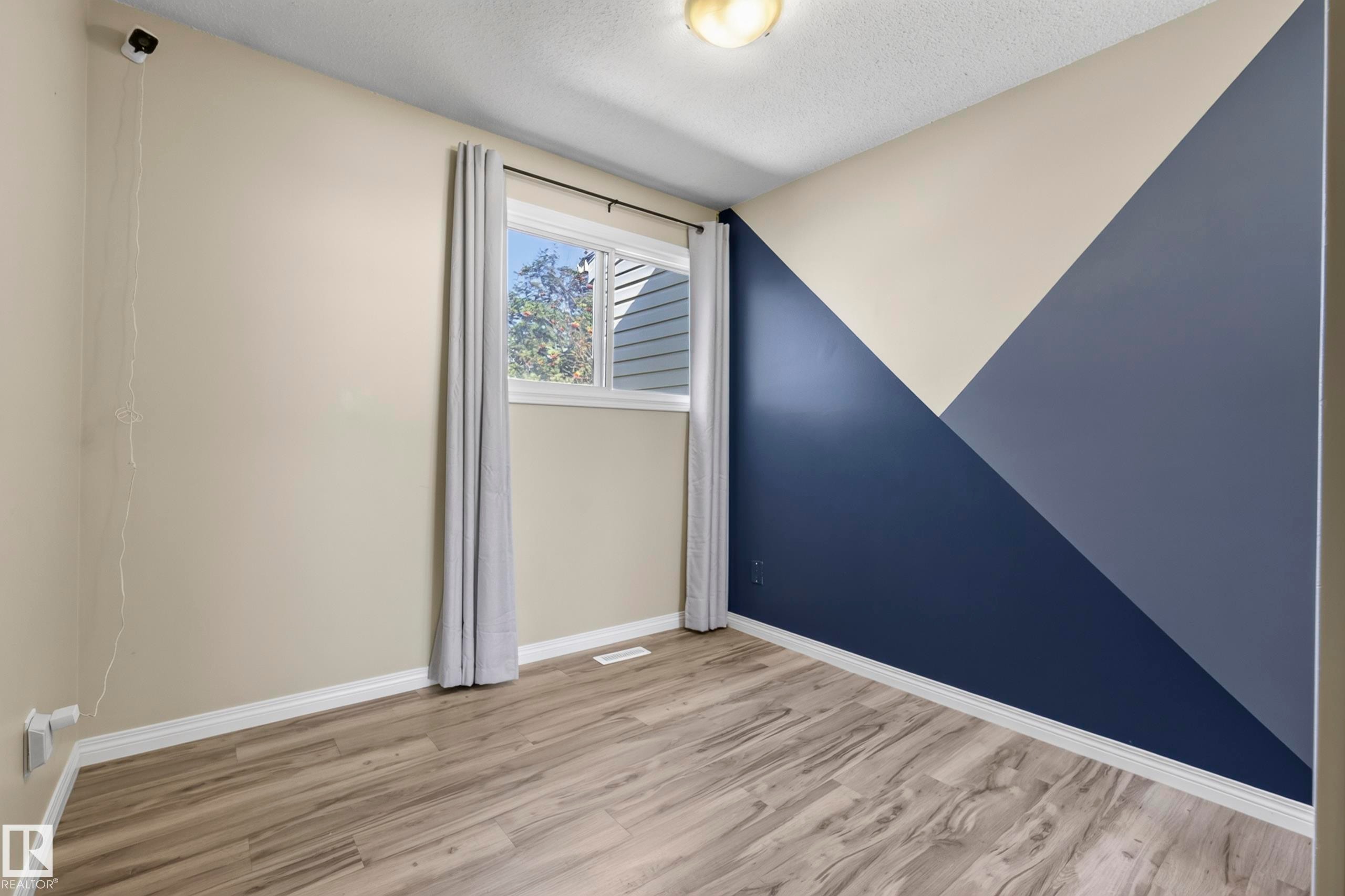 Wood-finish flooring, accent wall with geometric design, window with trim, and recessed ceiling light - 141 Dickinsfield Court Nw, Edmonton, AB