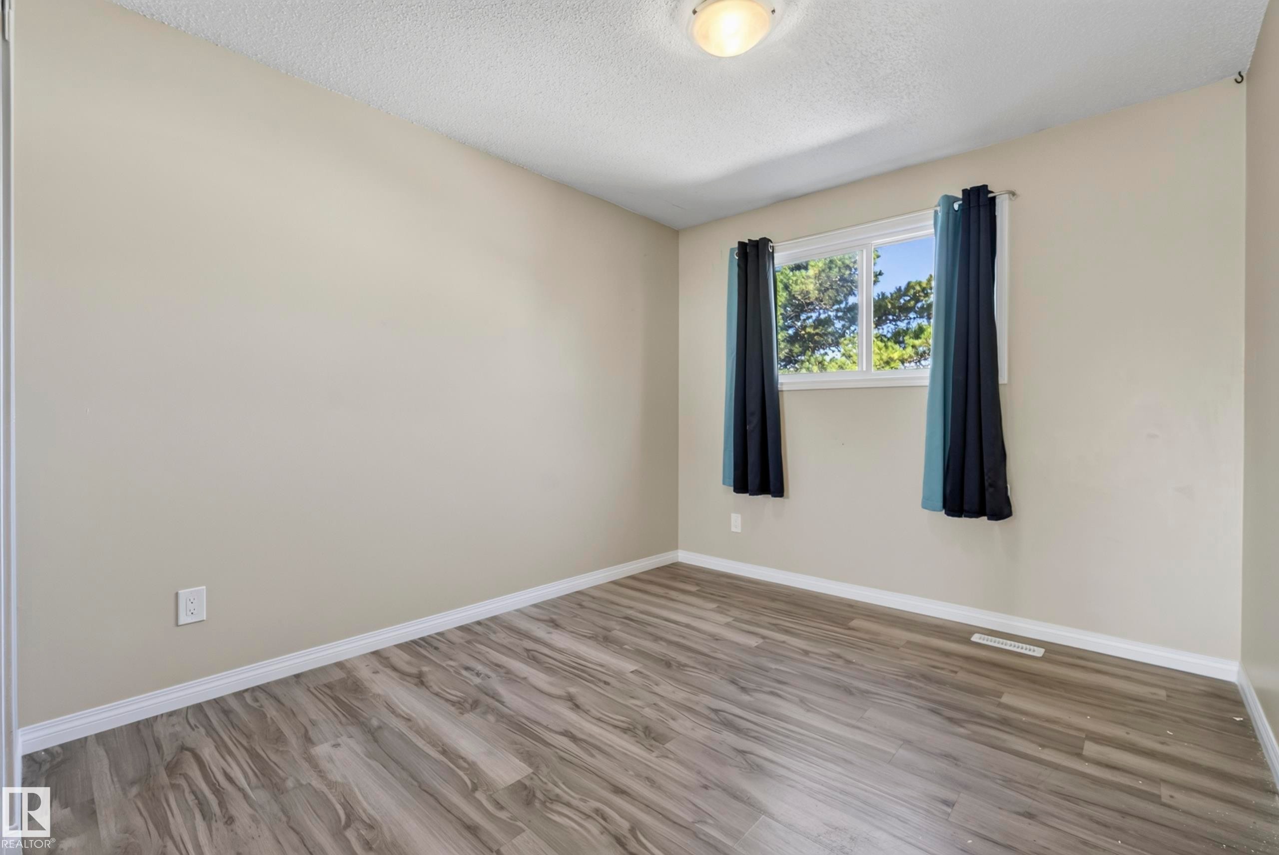 Neutral wall paint, wood-finish flooring, white trim, and a ceiling-mounted light fixture - 141 Dickinsfield Court Nw, Edmonton, AB