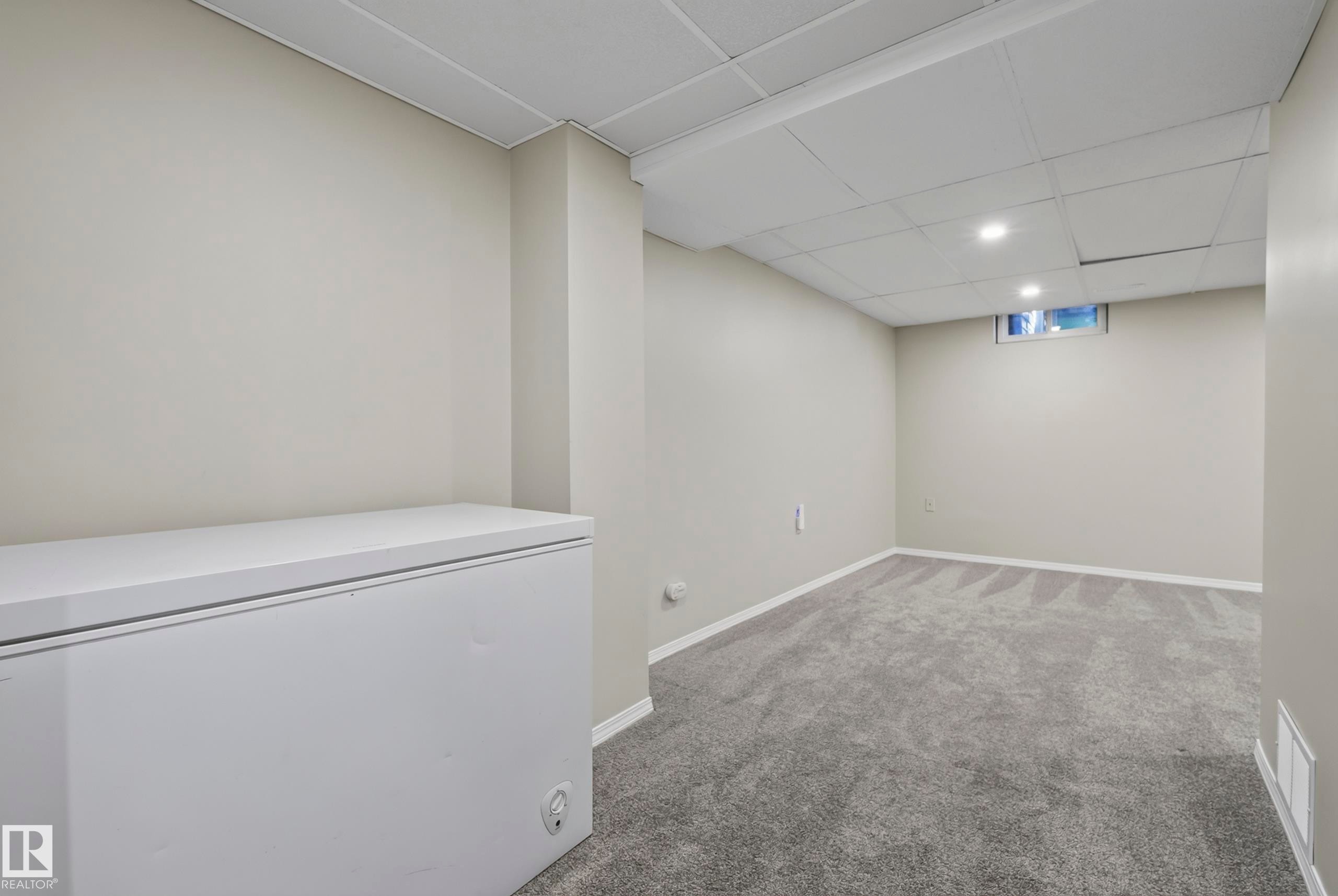 Recessed lighting, painted walls, carpet flooring, grid ceiling panels, and a window - 141 Dickinsfield Court Nw, Edmonton, AB