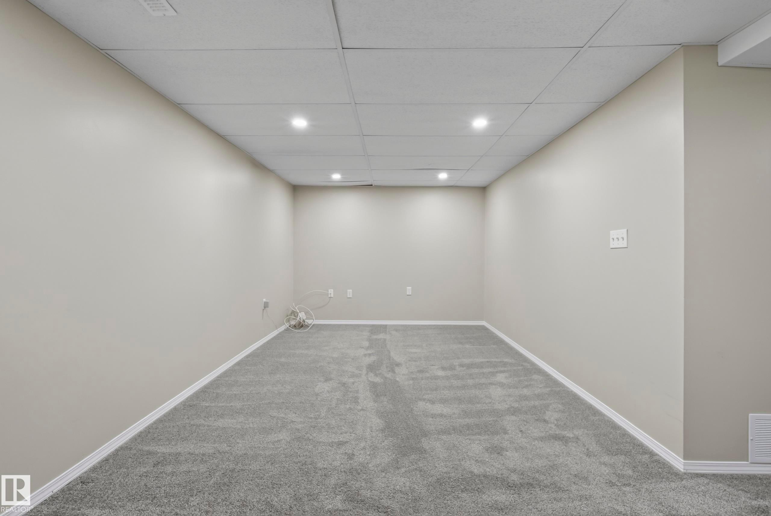 Recessed lighting and a drop ceiling complement the light gray walls and plush gray carpeting - 141 Dickinsfield Court Nw, Edmonton, AB