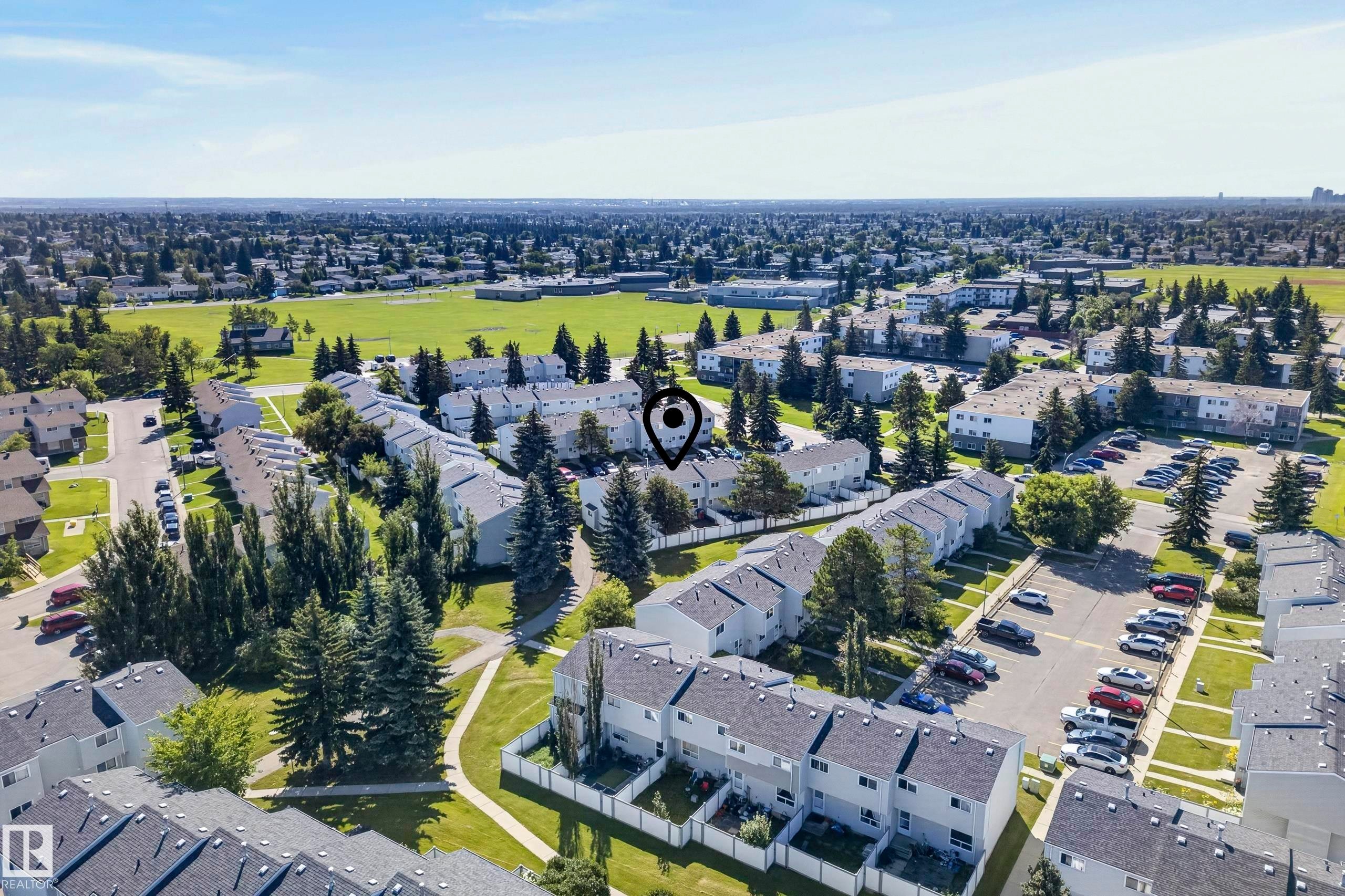 Townhome community with mature trees, green spaces, and surface parking areas - 141 Dickinsfield Court Nw, Edmonton, AB