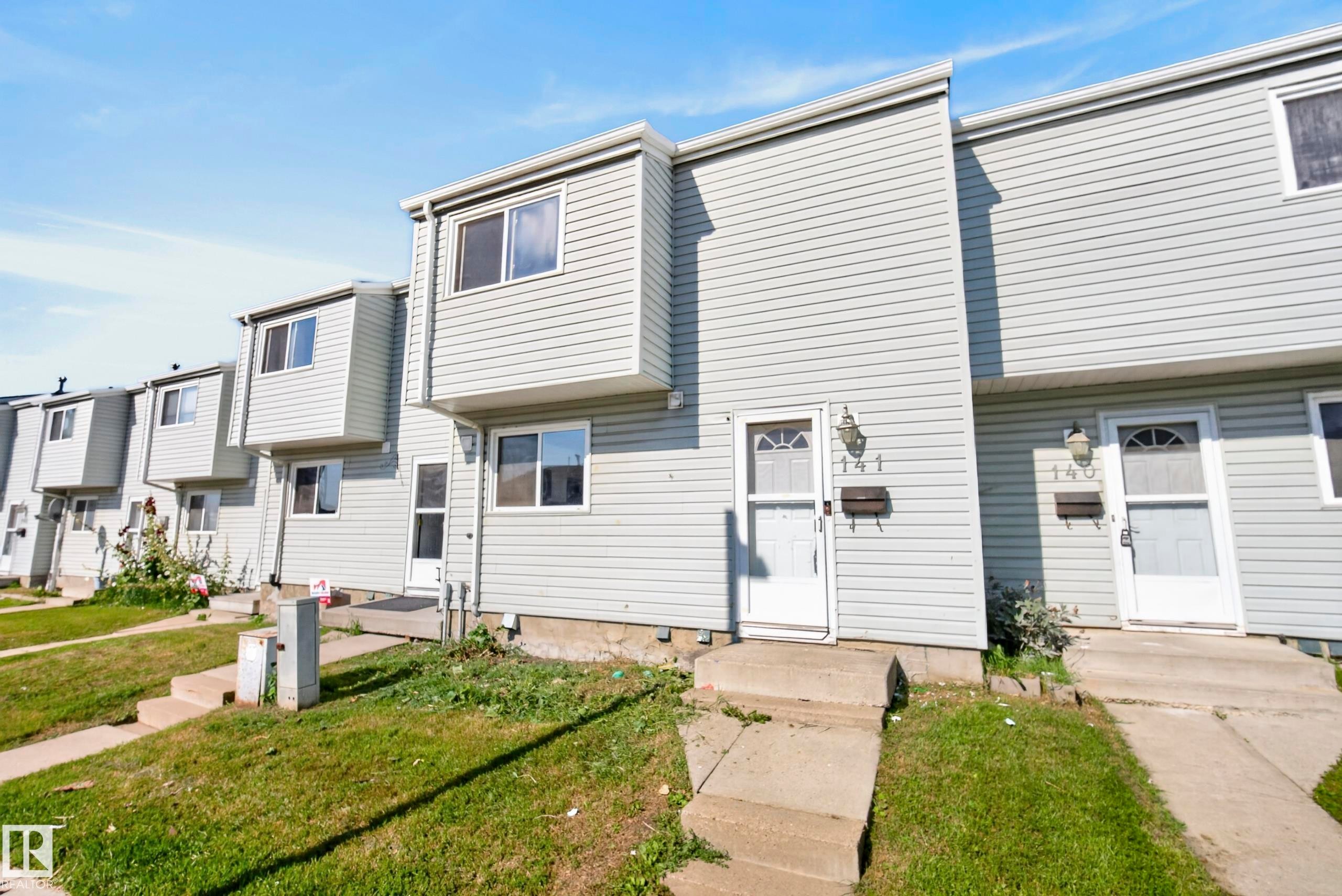 Vinyl siding exterior with a pitched roofline, multiple windows, and individual entryways - 141 Dickinsfield Court Nw, Edmonton, AB